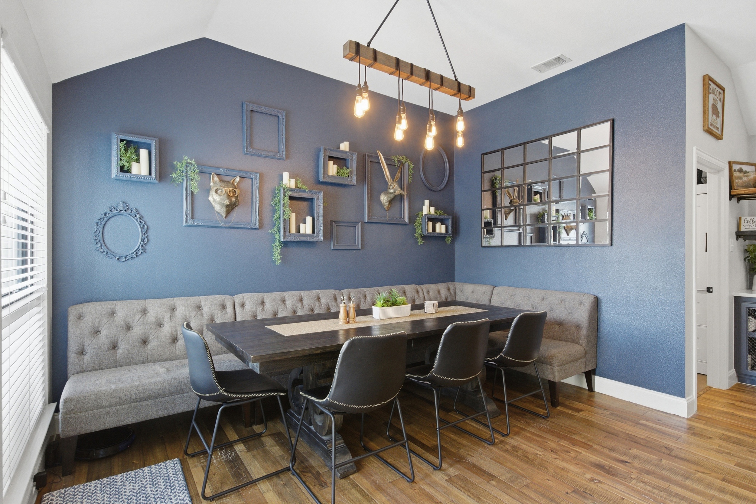 Open Dining Room featuring a Dining Table for 8, dramatic blue walls, a mirror gallery wall, and warm pendant lighting for memorable group dinners.
