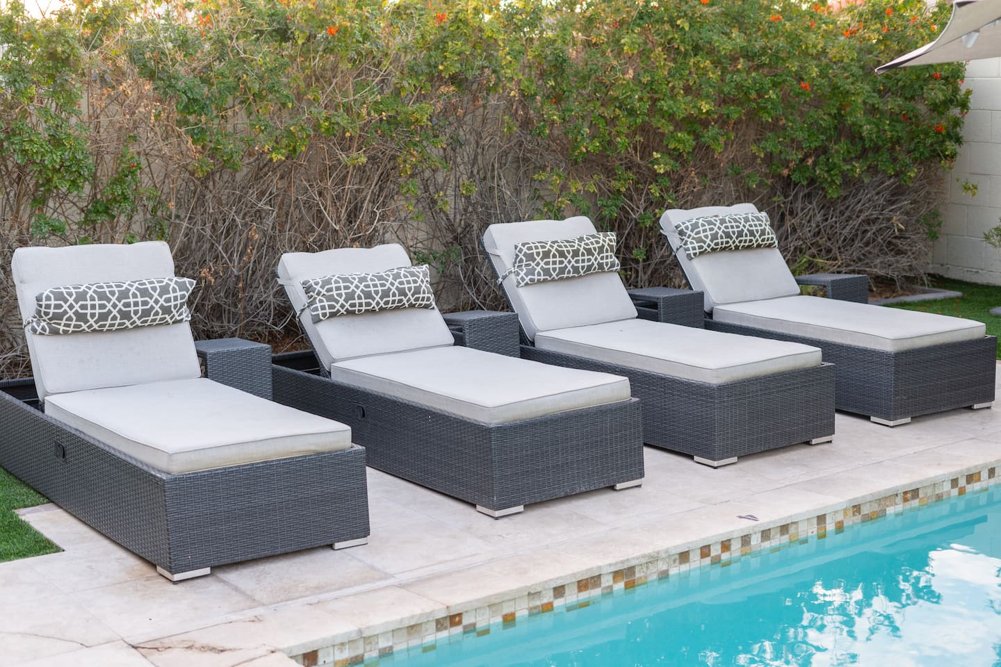 Four modern woven loungers with geometric head pillows invite you to soak up the sun just steps from the sparkling pool.