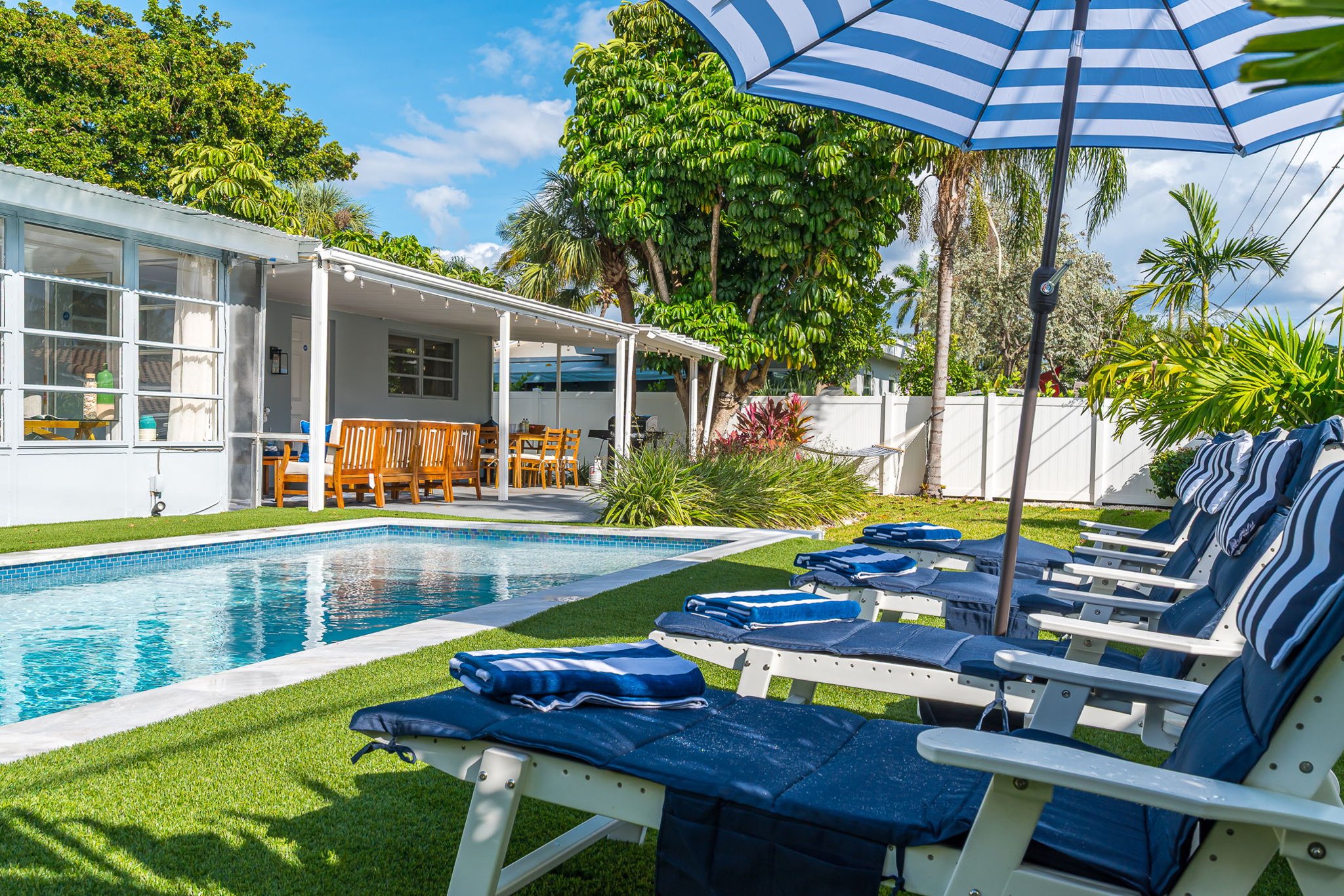 Dive into luxury with a sparkling heated saltwater pool, surrounded by lush palms, chic loungers, and modern turf for the perfect resort-style backyard escape.