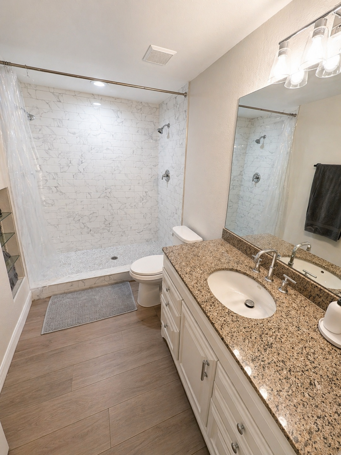 Bright and functional full bathroom featuring a spacious walk-in shower, granite vanity, and ample counter space. Clean finishes and good lighting make it perfect for everyday comfort and convenience.