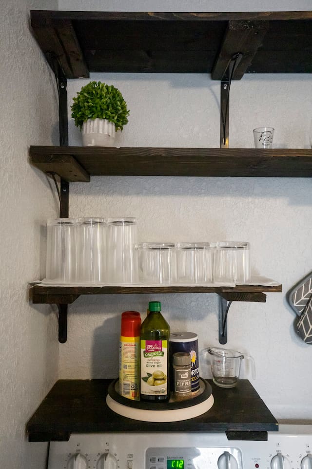 Open shelving stocked with glasses and cooking supplies, offering easy access to everything you need for dining and meal preparation.
