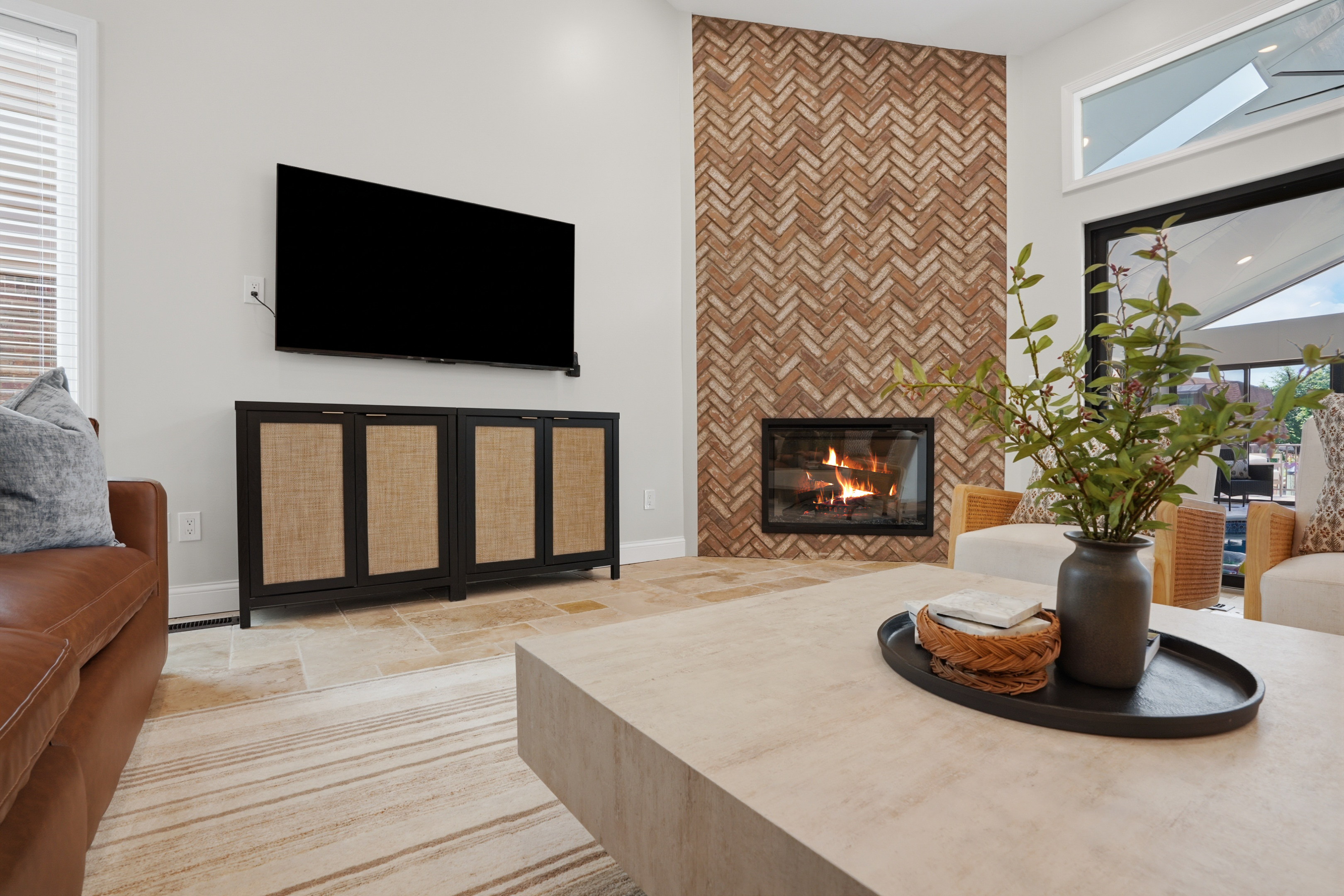 Modern open-concept living room with a sleek fireplace, textured accent wall, and large TV. Bright, stylish space with warm finishes and a cozy yet upscale atmosphere perfect for relaxing or entertaining.