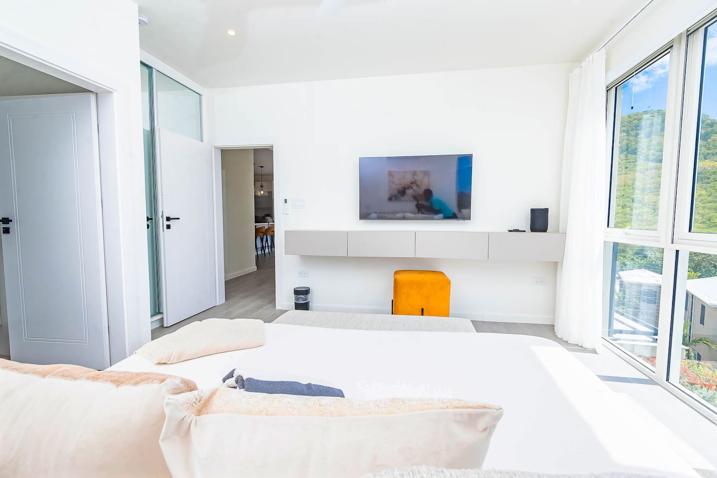 Master bedroom with king size bed, en-suite bathroom, air conditioning, ceiling fan, wall mounted tv, closet and gorgeous views of the ocean and hillside.