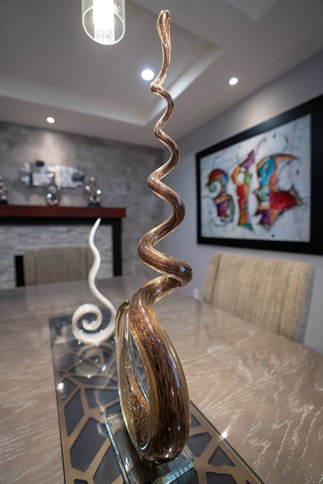  beautiful dining room with a glass sculpture on the table and a painting on the wall.