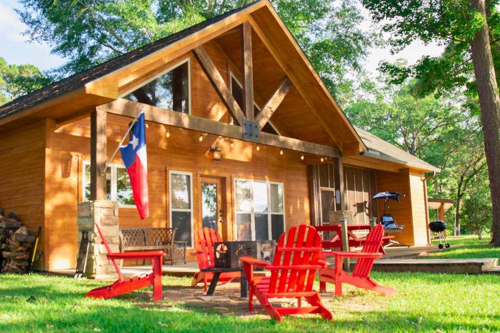 Lakefront cabin getaway with private dock, firepit & red Adirondack chairs — the Heart of Huxley Bay.