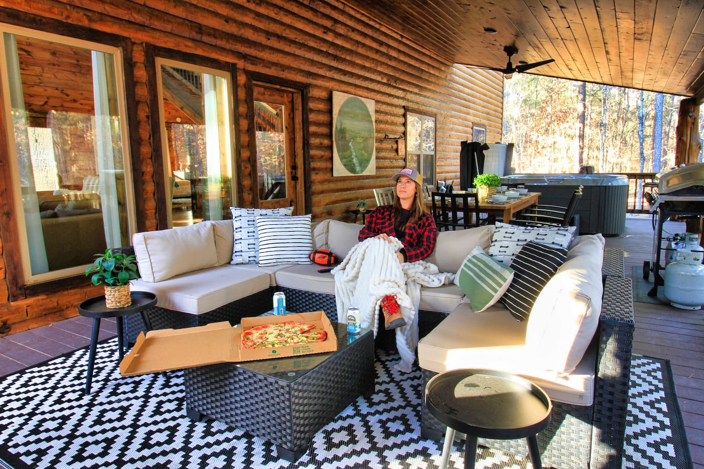 Outdoor living area with smart TV, cozy seating, and fireplace—perfect for relaxing, streaming, and enjoying family fun in the forest