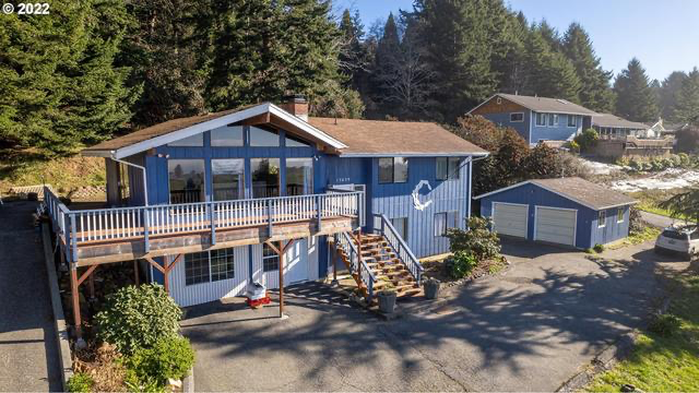 Coastal home framed by trees, steps from shimmering blue water.