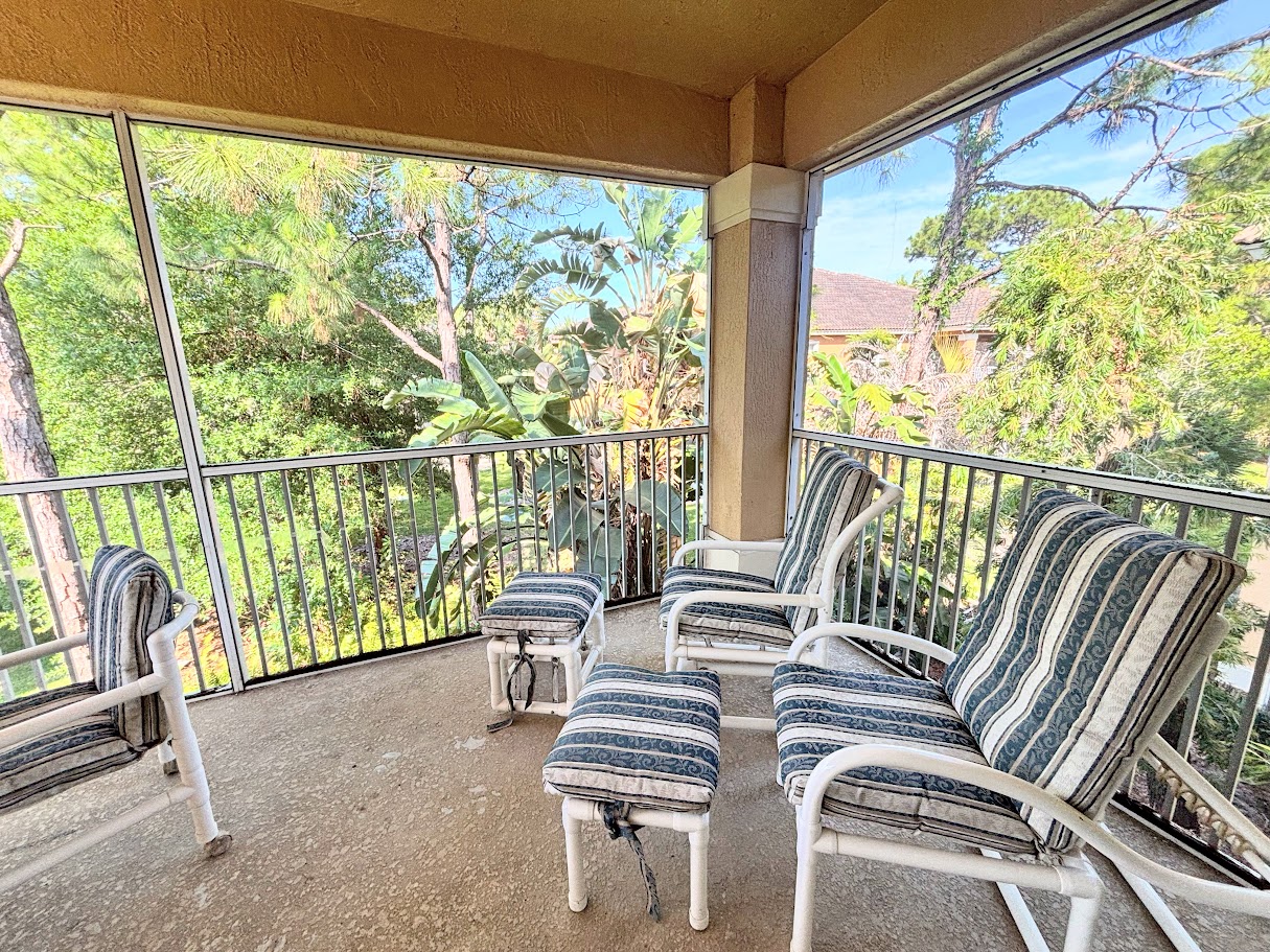 Private screened balcony with outdoor seating, offering a peaceful spot to relax and enjoy the surrounding greenery.