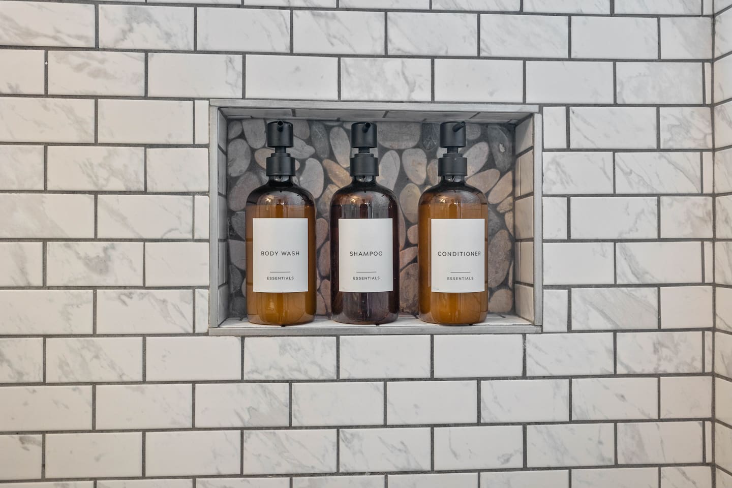 Elegant bathroom display featuring stylish body wash, conditioner, and shampoo bottles, perfectly arranged for easy access. The modern design and thoughtful presentation create a luxurious spa-like experience for guests during their stay.