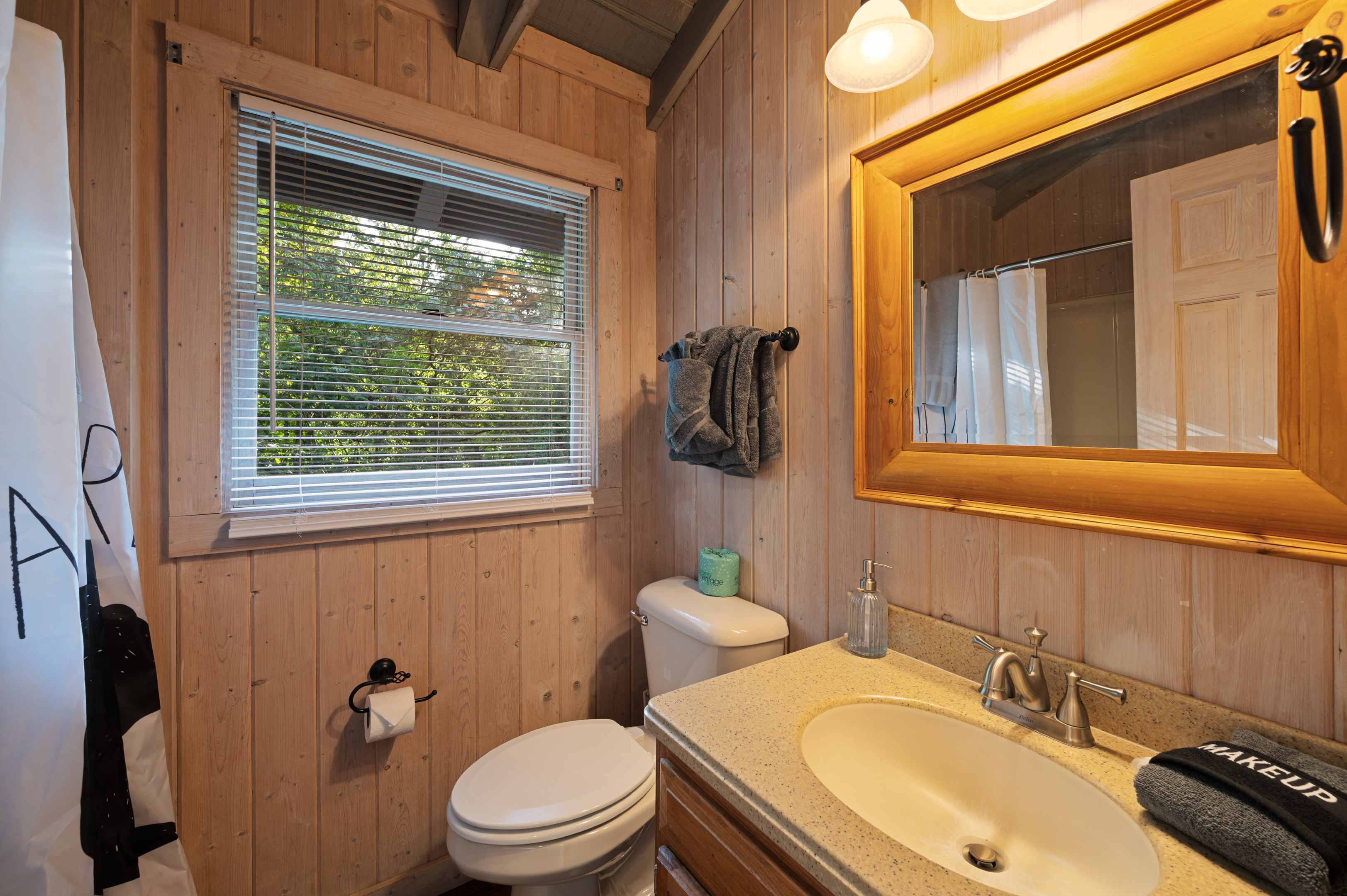 Relax in this charming wood-paneled bath with refreshing forest views.