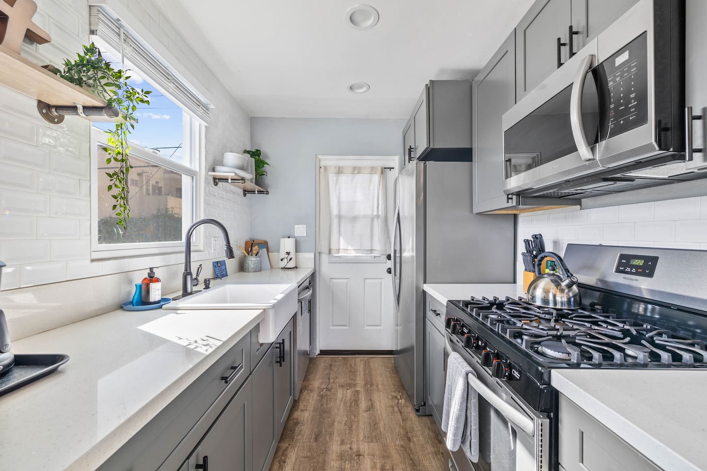 Stylish kitchen equipped with a modern stove featuring a microwave above and an oven below. A sleek refrigerator and coffee maker complement the space, while neatly arranged plates, cups, and utensils ensure convenience for all your culinary needs.