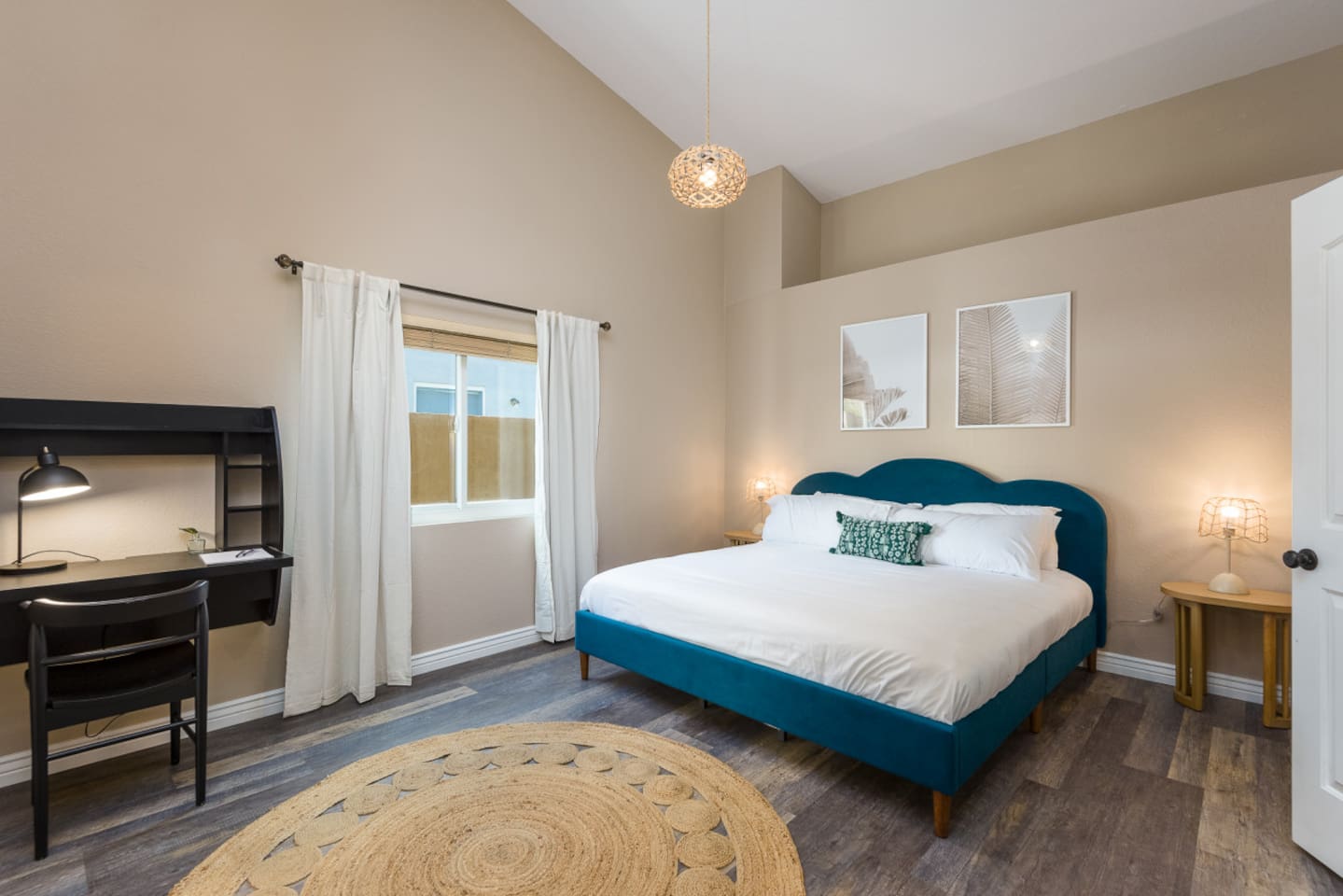 Primary ensuite bedroom with a spacious bed, dedicated workspace, high ceilings, and a bright, open layout for a comfortable stay.
