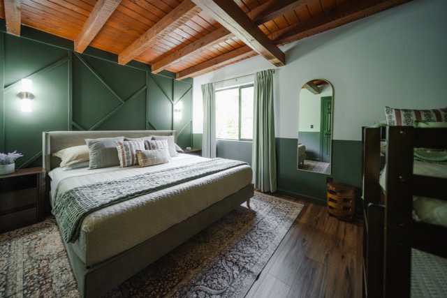 A bedroom featuring a king bed and twin-over-twin bunk bed, offering a comfortable setup for families.