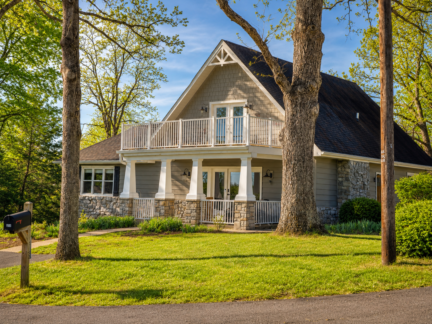Welcoming front exterior with a covered porch, large yard and a peaceful wooded setting near the lake.