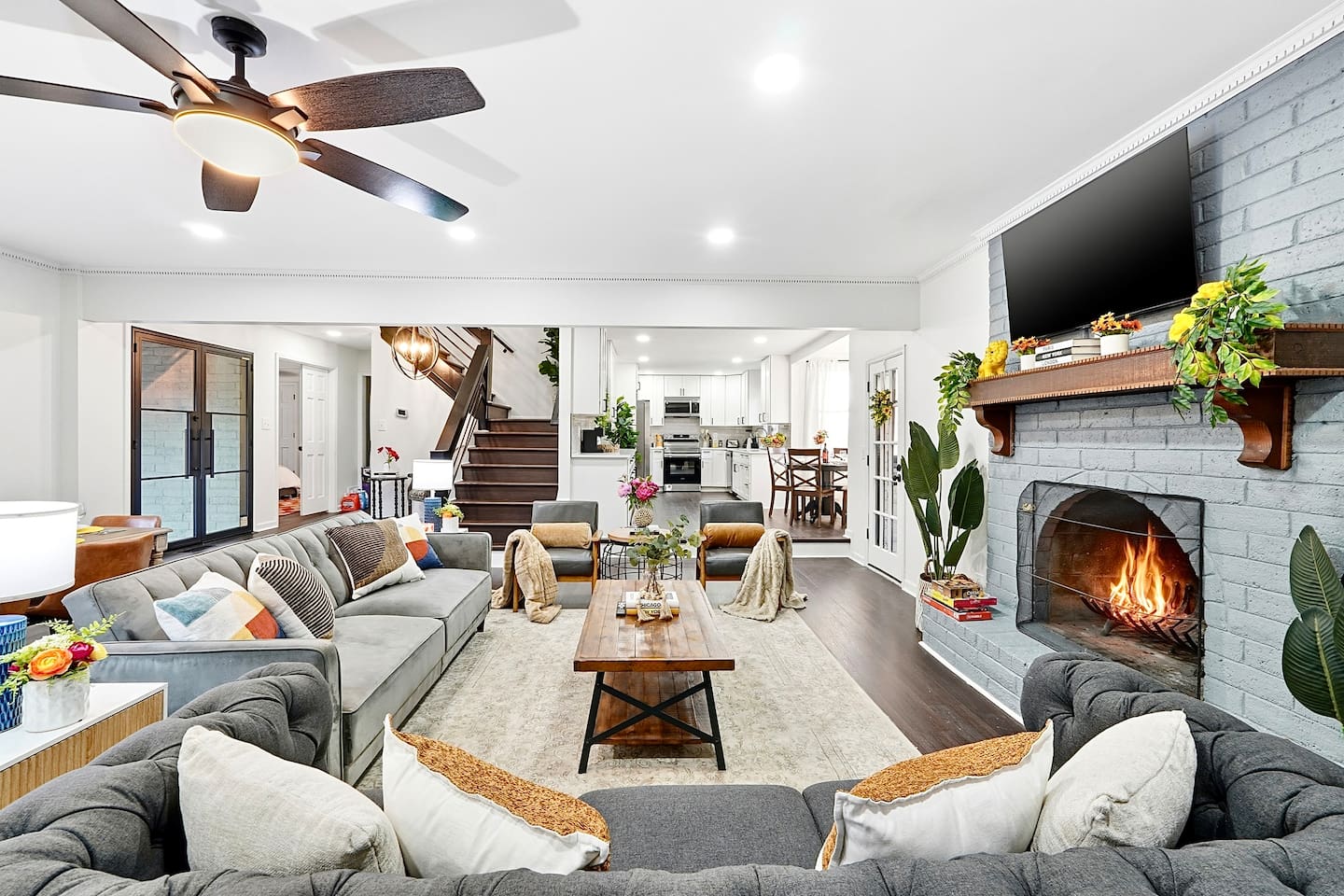 Warm and welcoming living room with two comfortable couches, two chairs, indoor plants, a cozy fireplace, and a TV powered by Google TV. Conveniently located as you walk through the front door and straight ahead from the primary side entrance. 