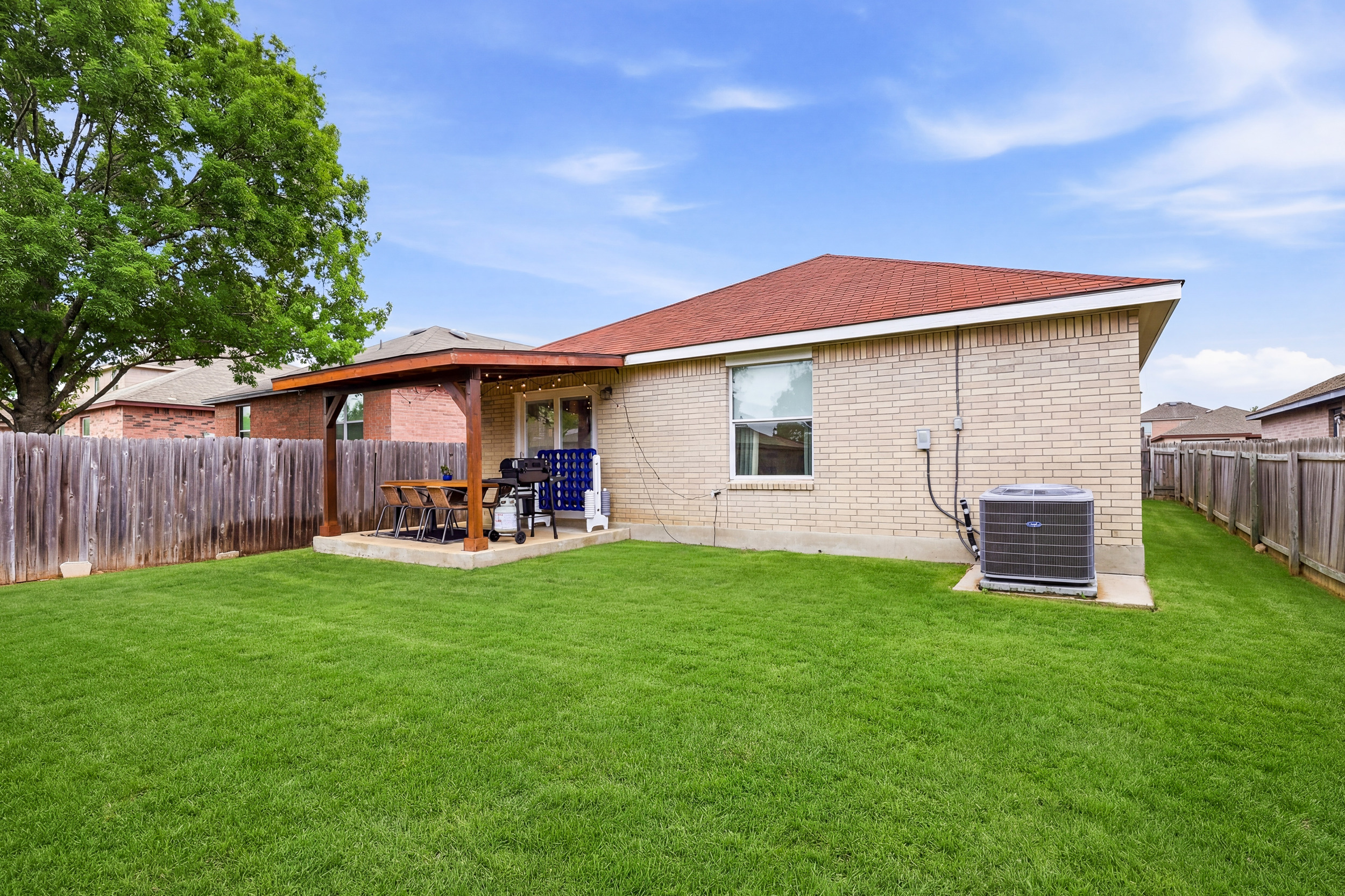 Fully fenced backyard with manicured lawn, covered wood-beam patio, and BBQ grill. Private, quiet, and spacious — one of the best features of this Northwest San Antonio home.