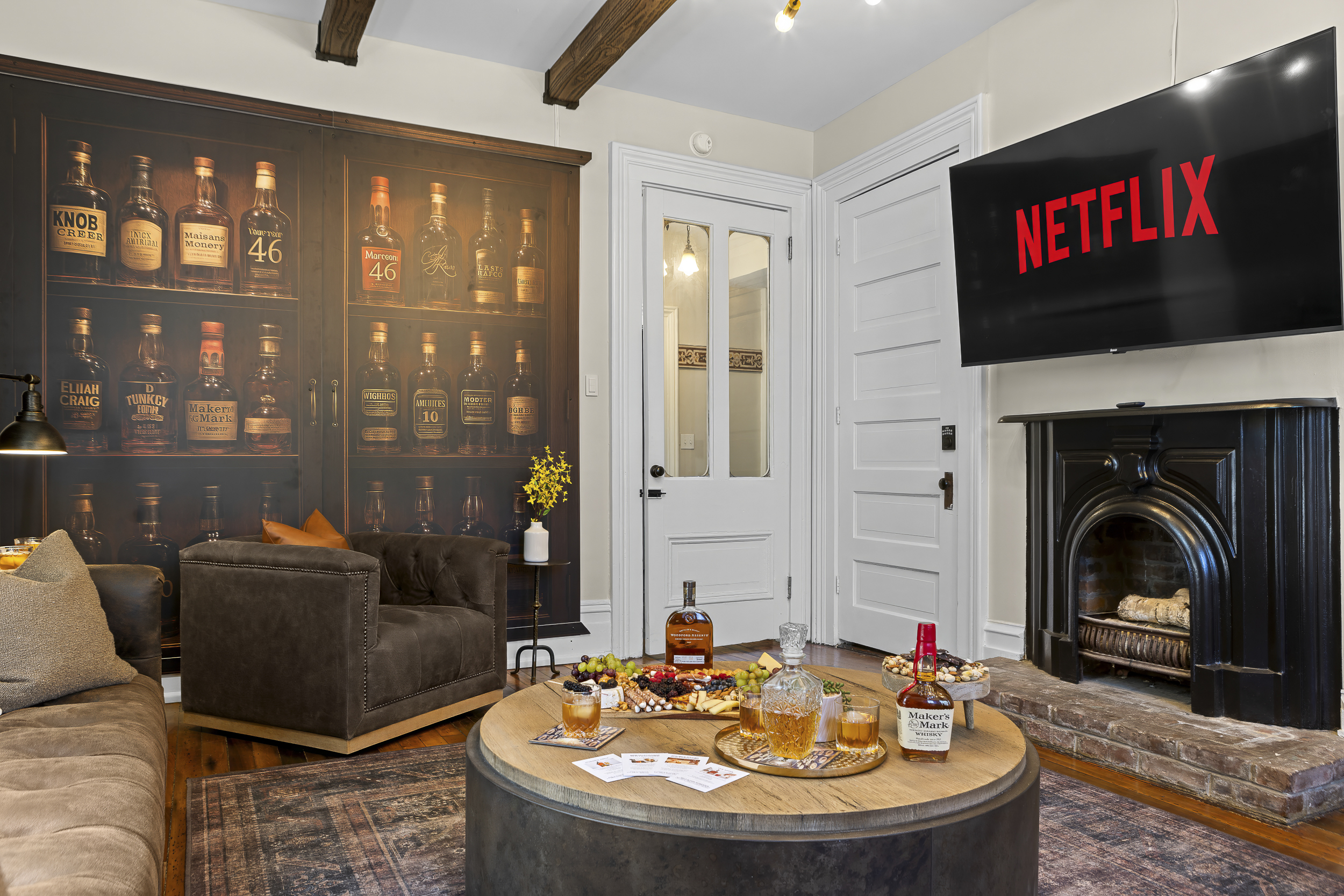 A smart TV above the original fireplace and a barrel-top coffee table at the center make movie nights easy and inviting.