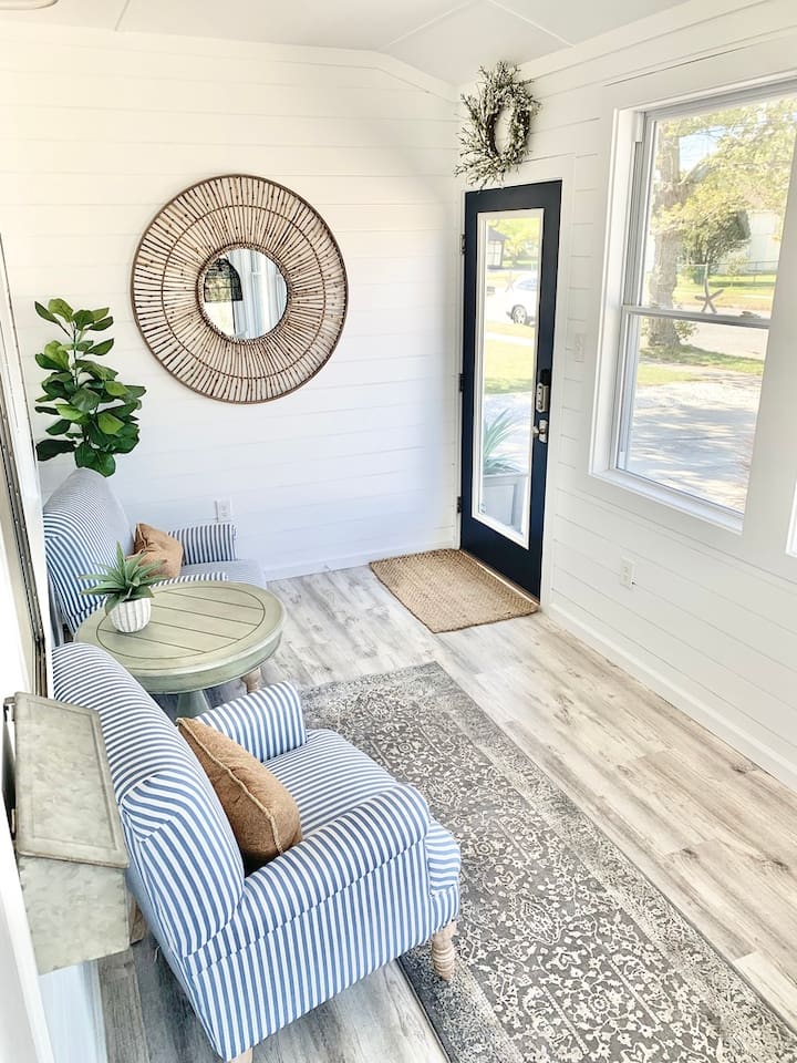 Enjoy a quiet moment in our bright sunroom, featuring comfortable blue-and-white striped armchairs and a classic pedestal side table. This cozy nook is perfect for morning coffee or getting lost in a good book.