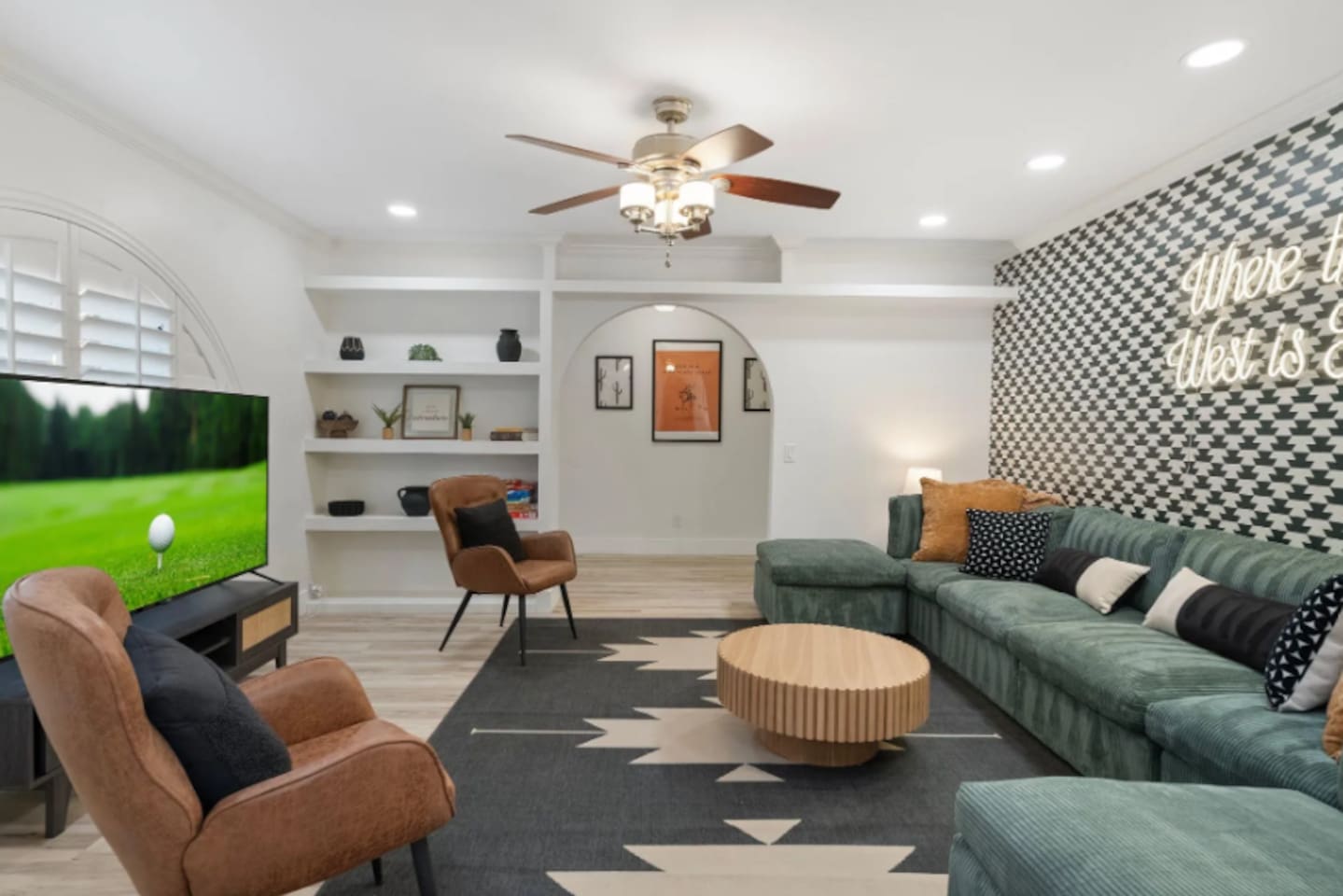 Sink into the deep green sectional and let the evening unwind. Desert-inspired art peeks through the archway, a bold houndstooth wall sets the mood, and the neon glow overhead makes it clear this room was made for gathering