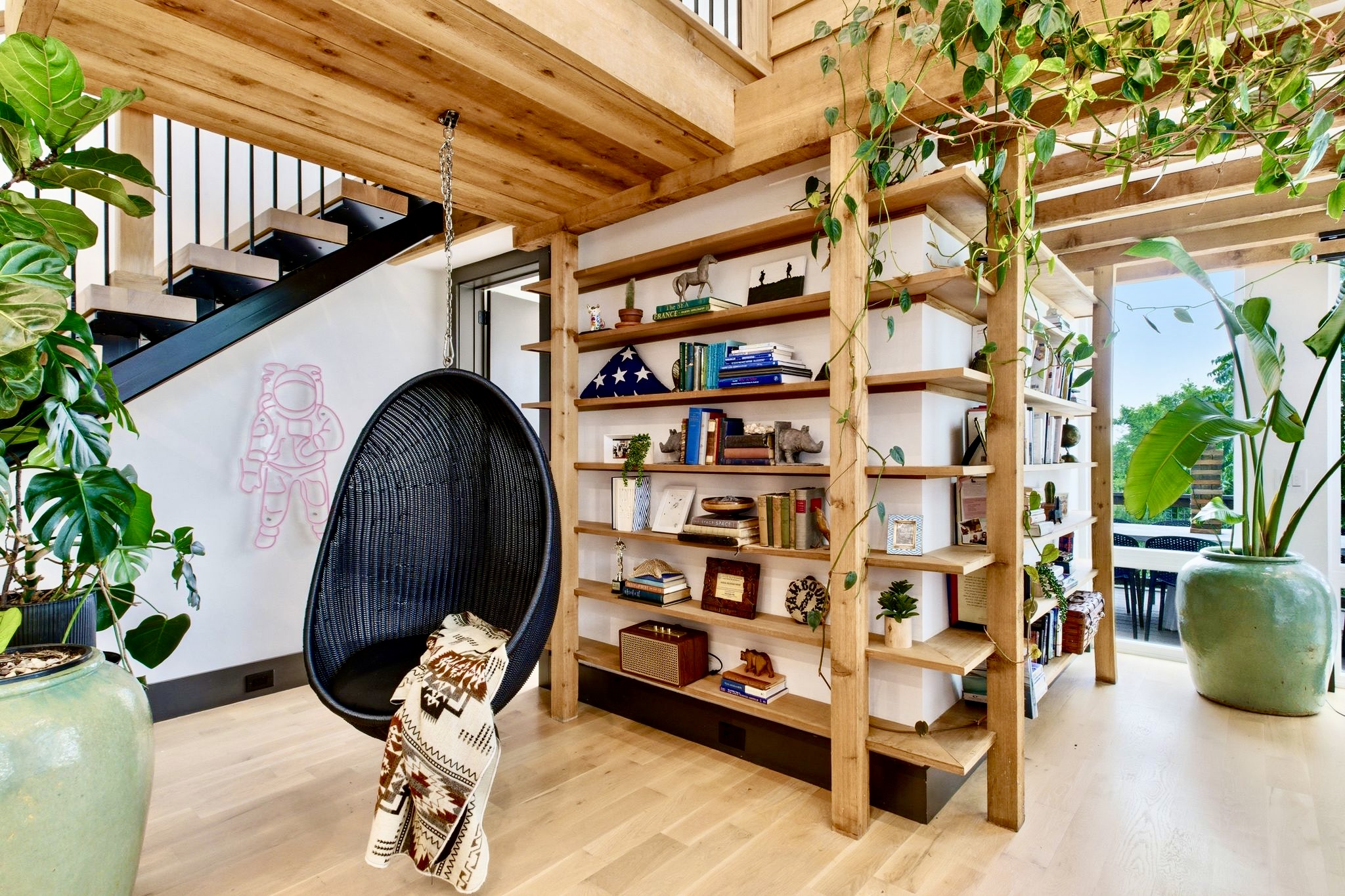Warm, plant-lined entryway w/ exposed wood shelving & a hanging chair — a welcoming first impression.
