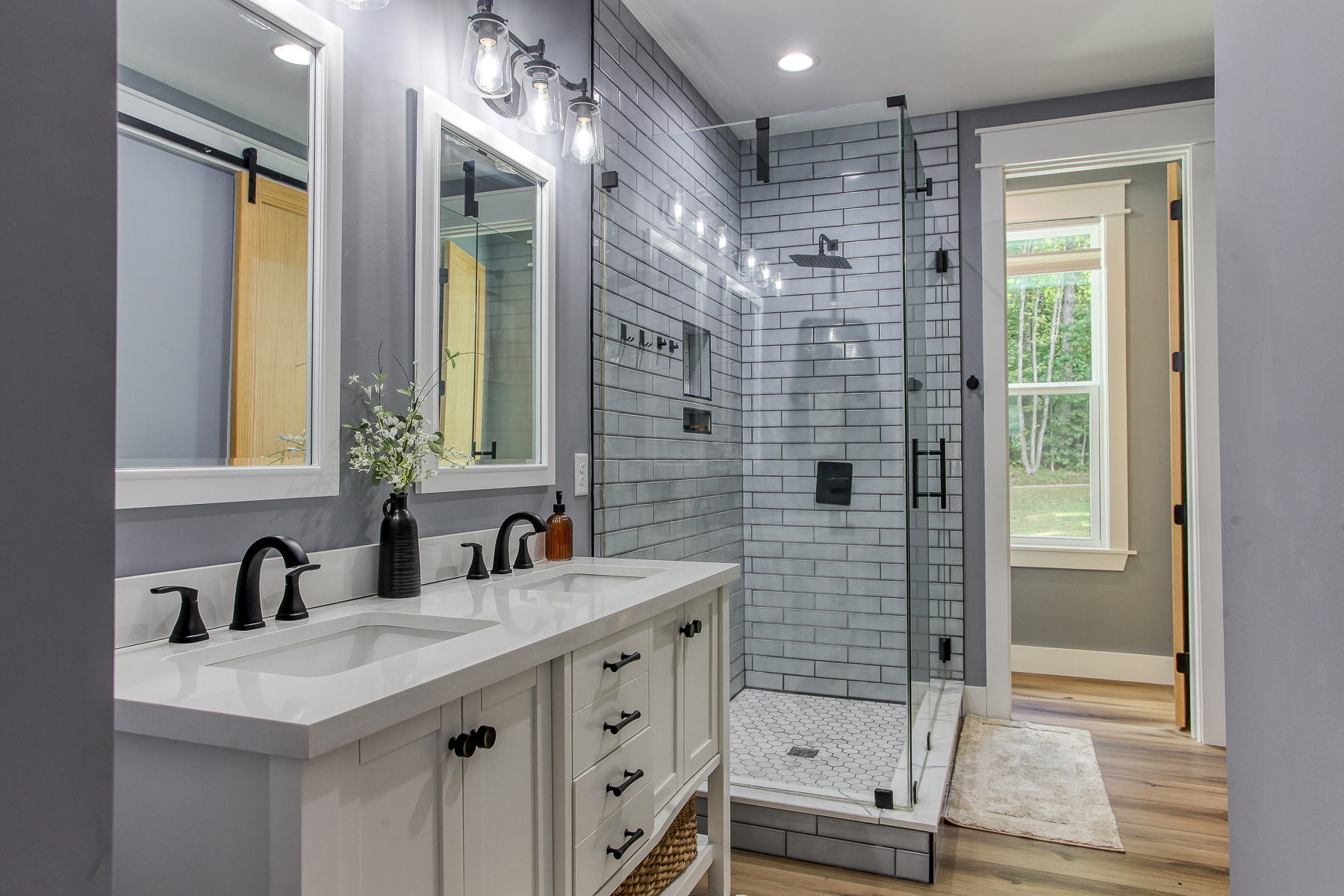 A double vanity and glass-enclosed walk-in shower make getting ready easy in the primary bathroom at Robbin’s Nest on Snowbird Creek.