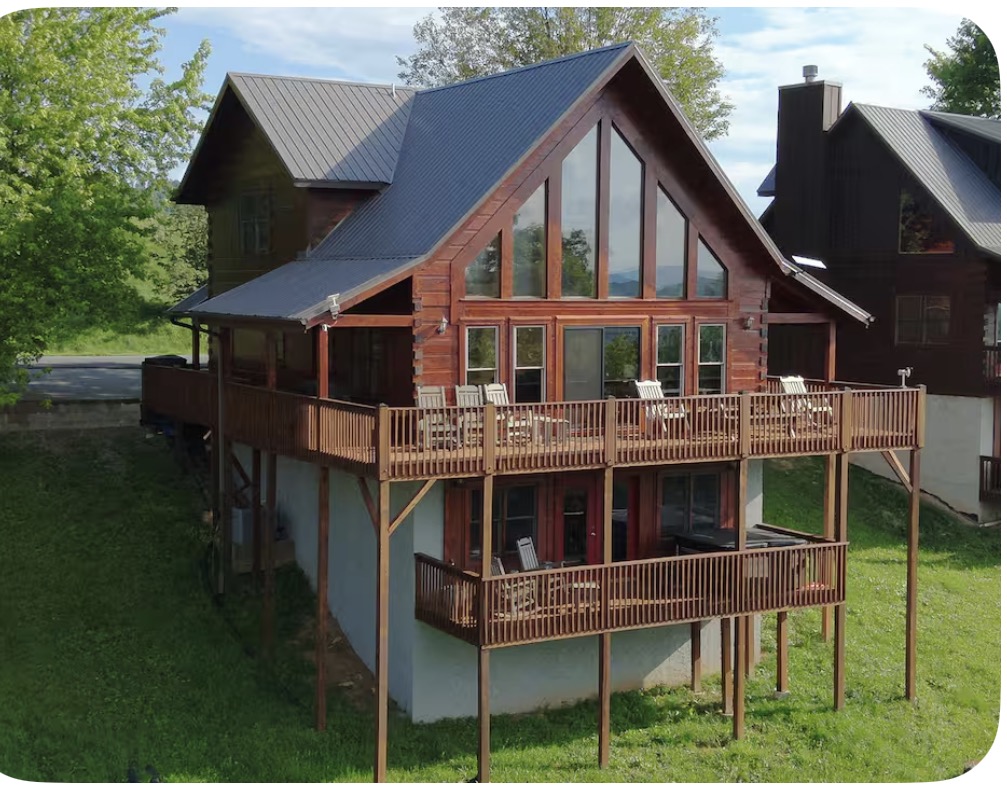 Rear view of the three-level mountain cabin and its outdoor deck spaces surrounded by the Scenic Wolf landscape.