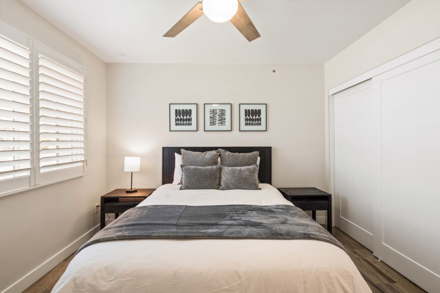 Comfortable guest room with a queen bed, ceiling fan, and closet storage nearby.