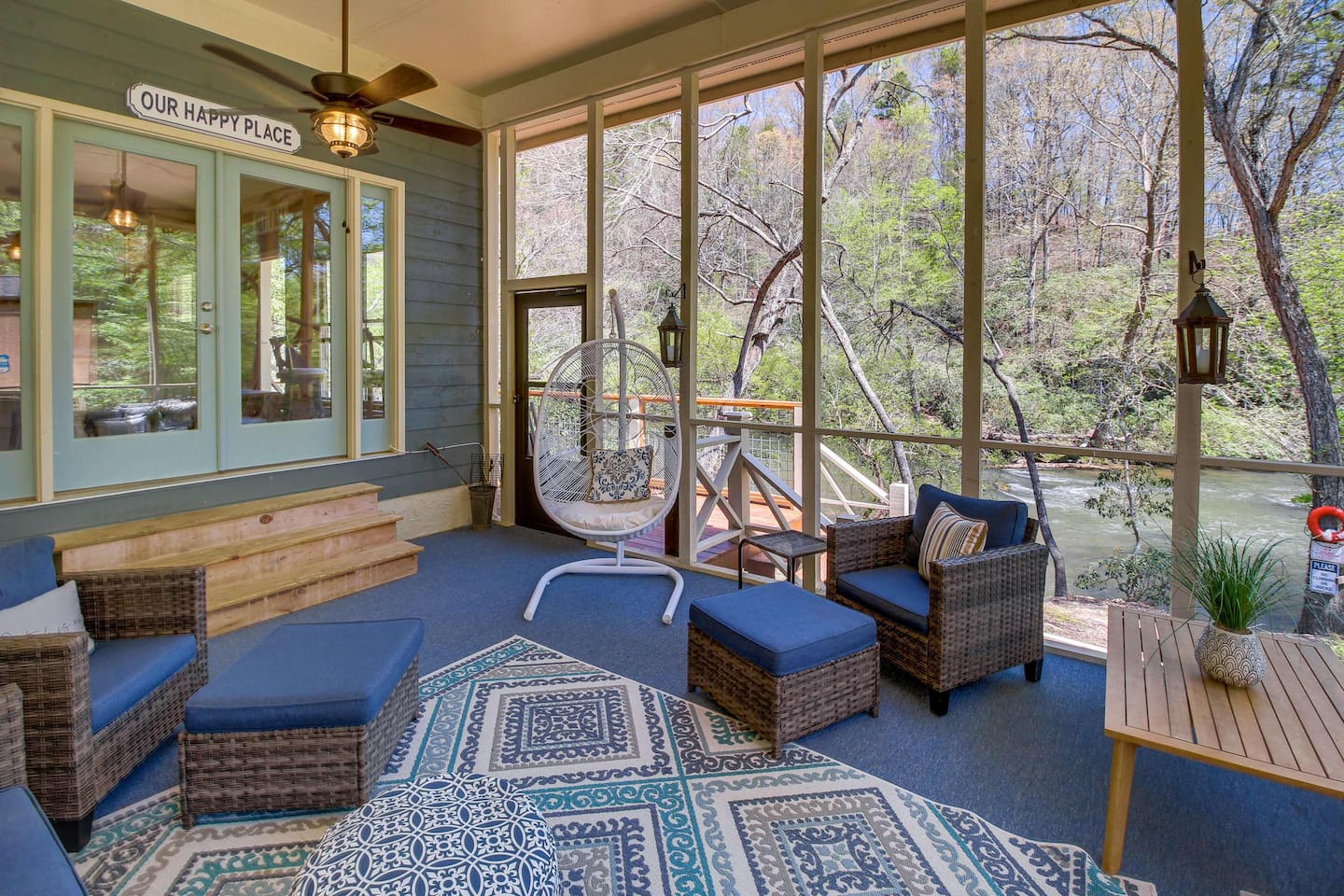 A cozy screened-in porch that overlooks the river, offering a perfect blend of comfort and nature. Enjoy the soothing sound of the water from the hanging swing chair or relax in the stylish wicker seating — an ideal spot to unwind with a morning cup
