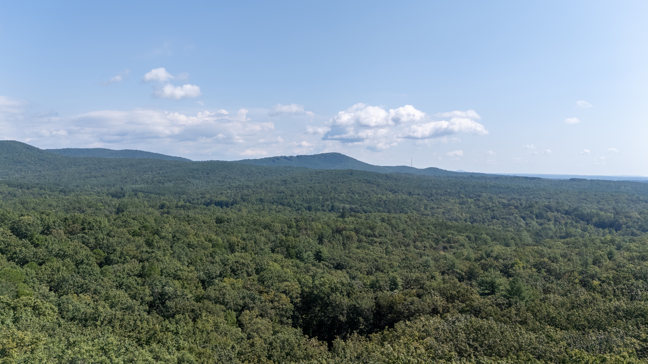Drone view of Heart Ridge on 8 wooded acres with mountain scenery in the distance.