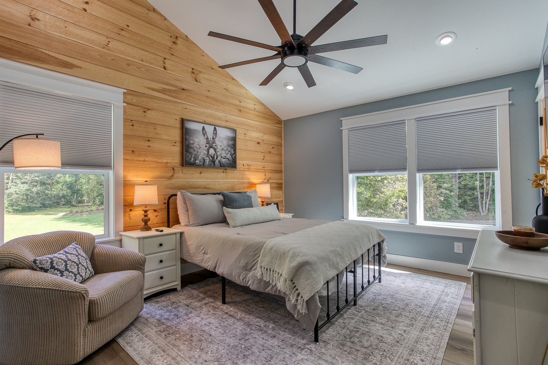 Unwind in an upstairs queen bedroom at Robbin’s Nest on Snowbird Creek, featuring a vaulted ceiling, wood accent wall, and a comfortable reading chair.