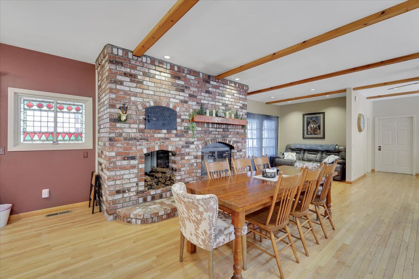 Dining area with a large table, brick fireplace, and easy access to the living room.
