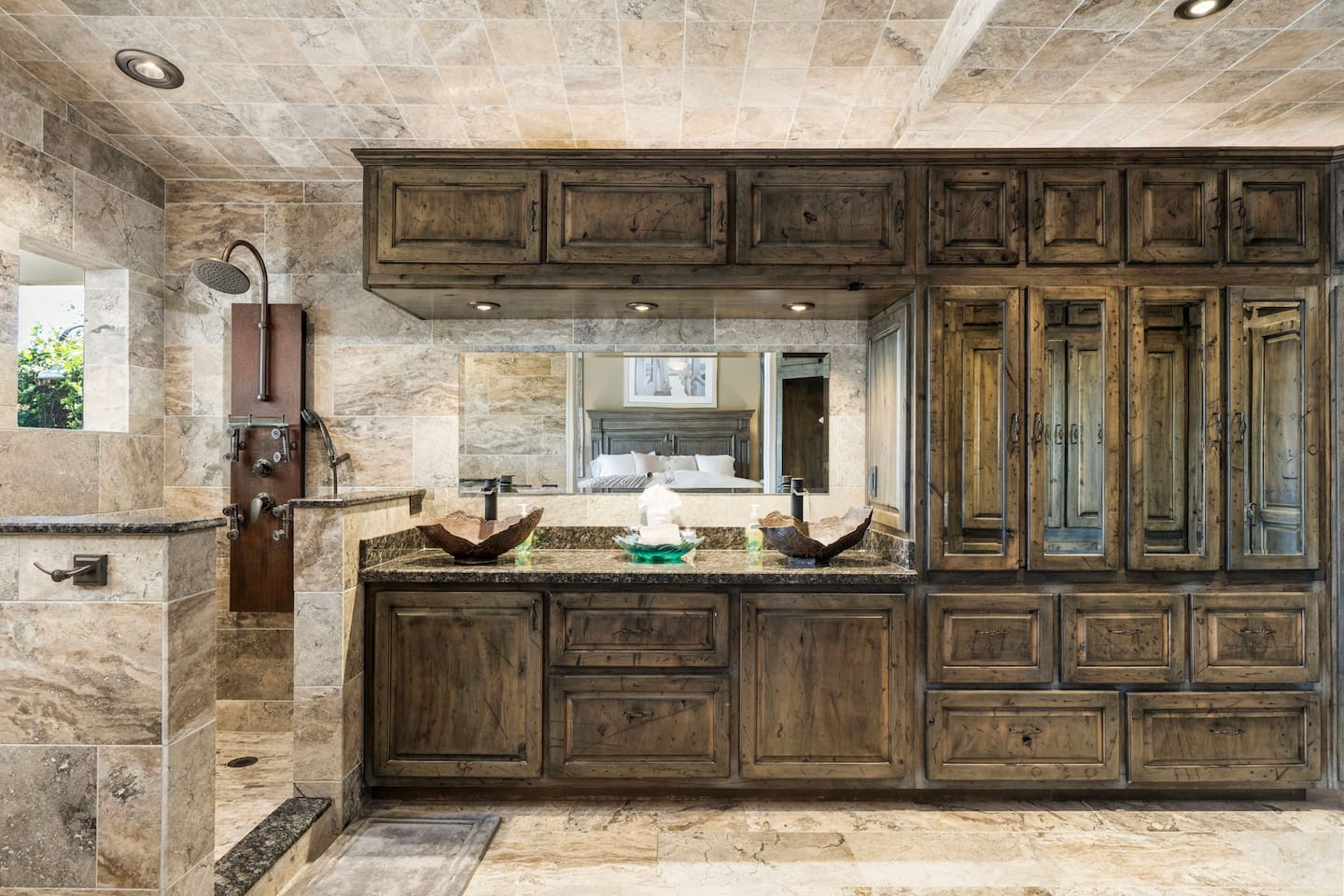 Step into the primary ensuite and feel the stress melt away — floor-to-ceiling travertine stone, dual vessel sinks, and rich wood cabinetry create a spa-like retreat you'll never want to leave.
