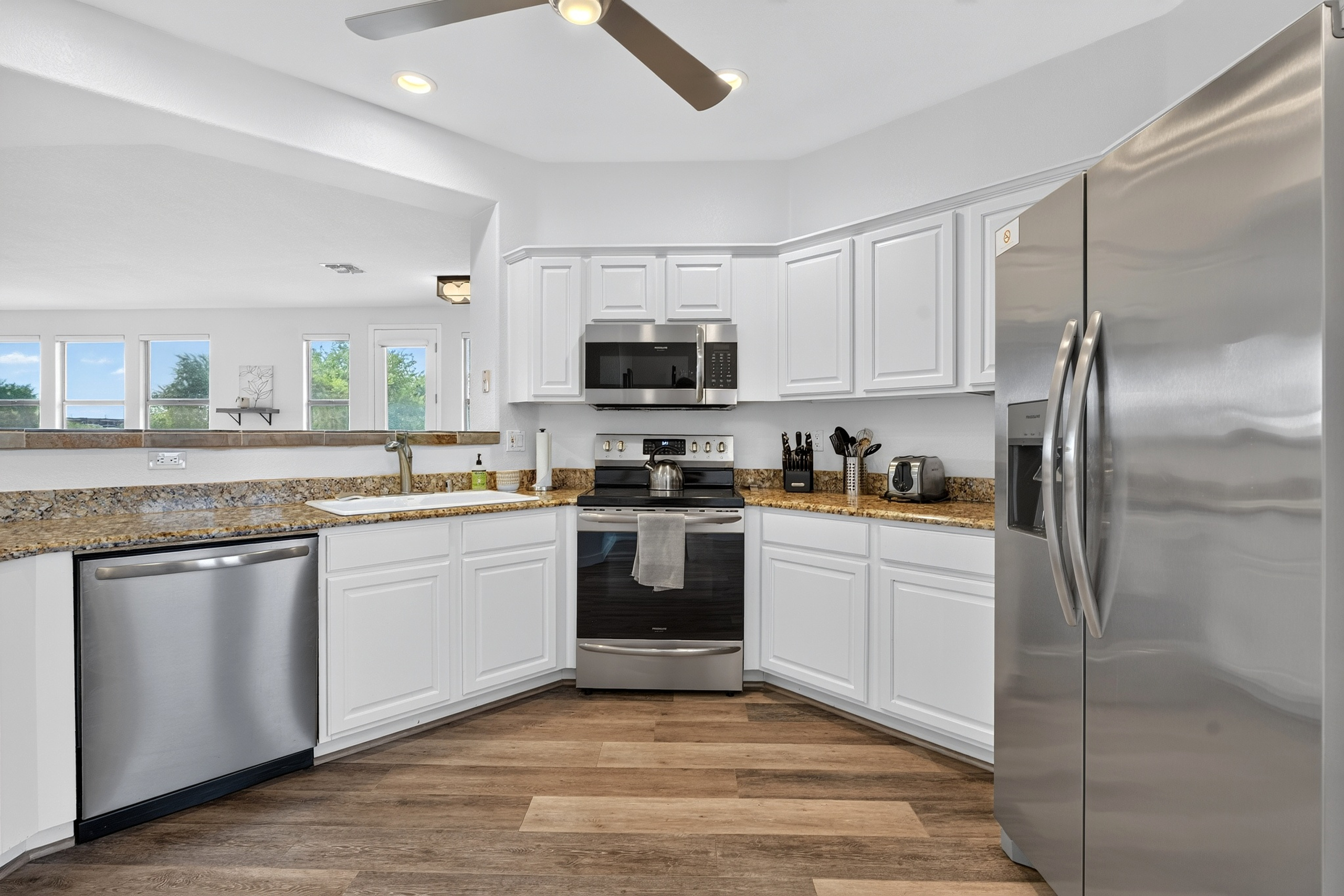 Kitchen with stainless steel appliances, dishwasher, granite counters, and open views into the living area.