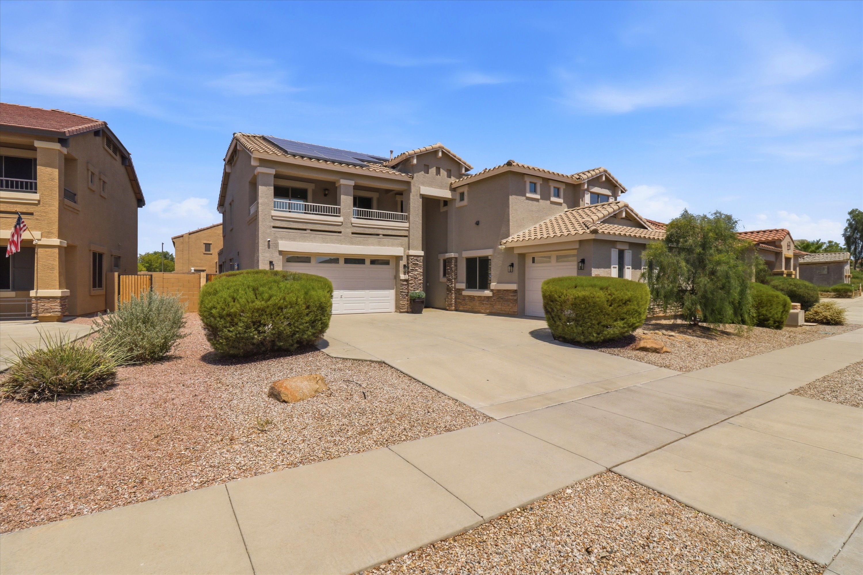 Front exterior with a wide driveway, garage access, and low-maintenance desert landscaping.
