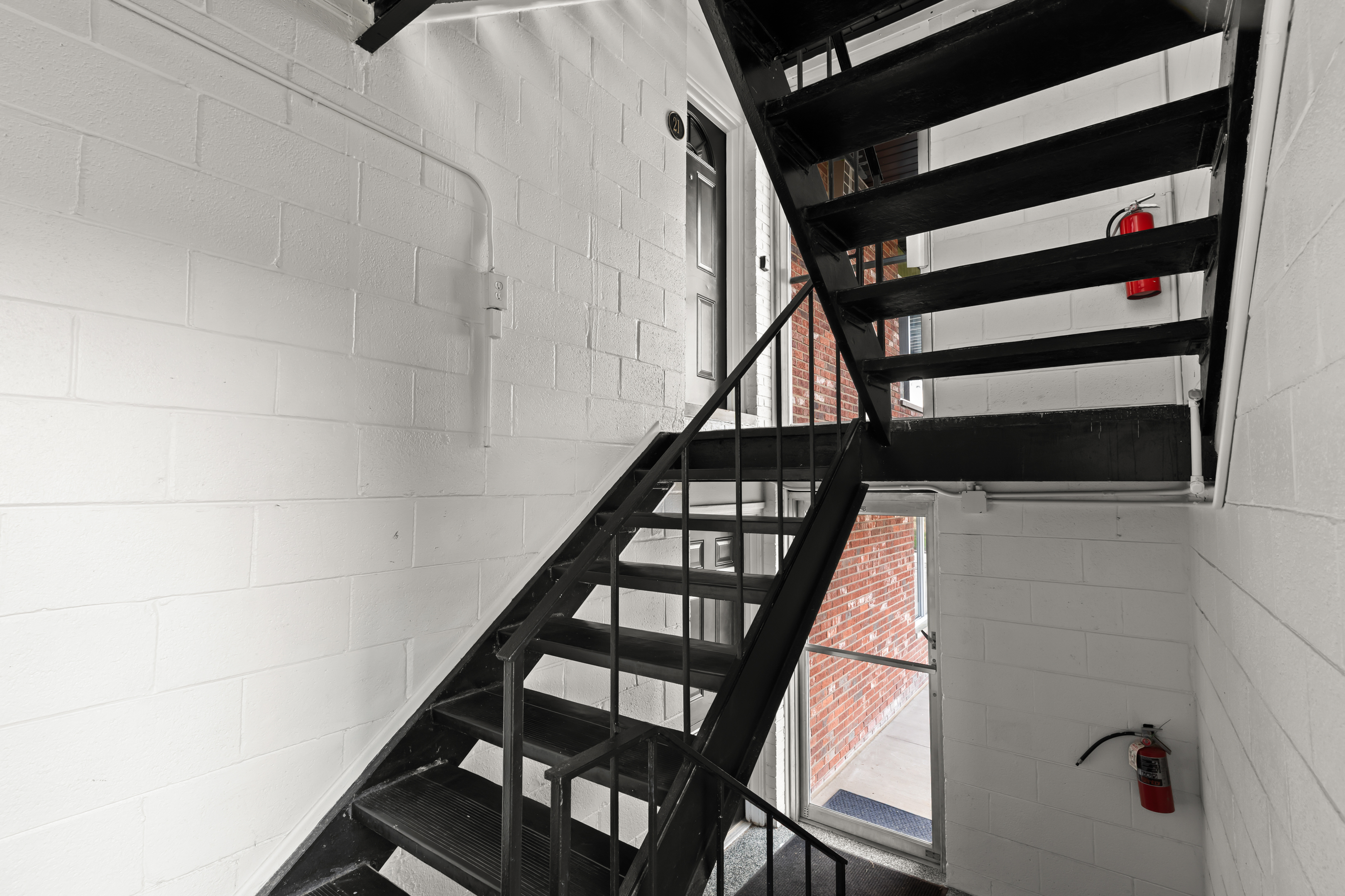 Well-lit stairwell with black metal steps and large windows for natural light