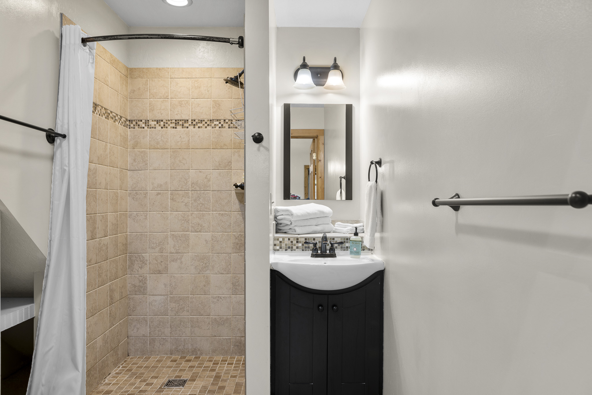 Charming Bathroom Retreat: Modern tiles, sleek vanity, and fresh towels await your stay!

