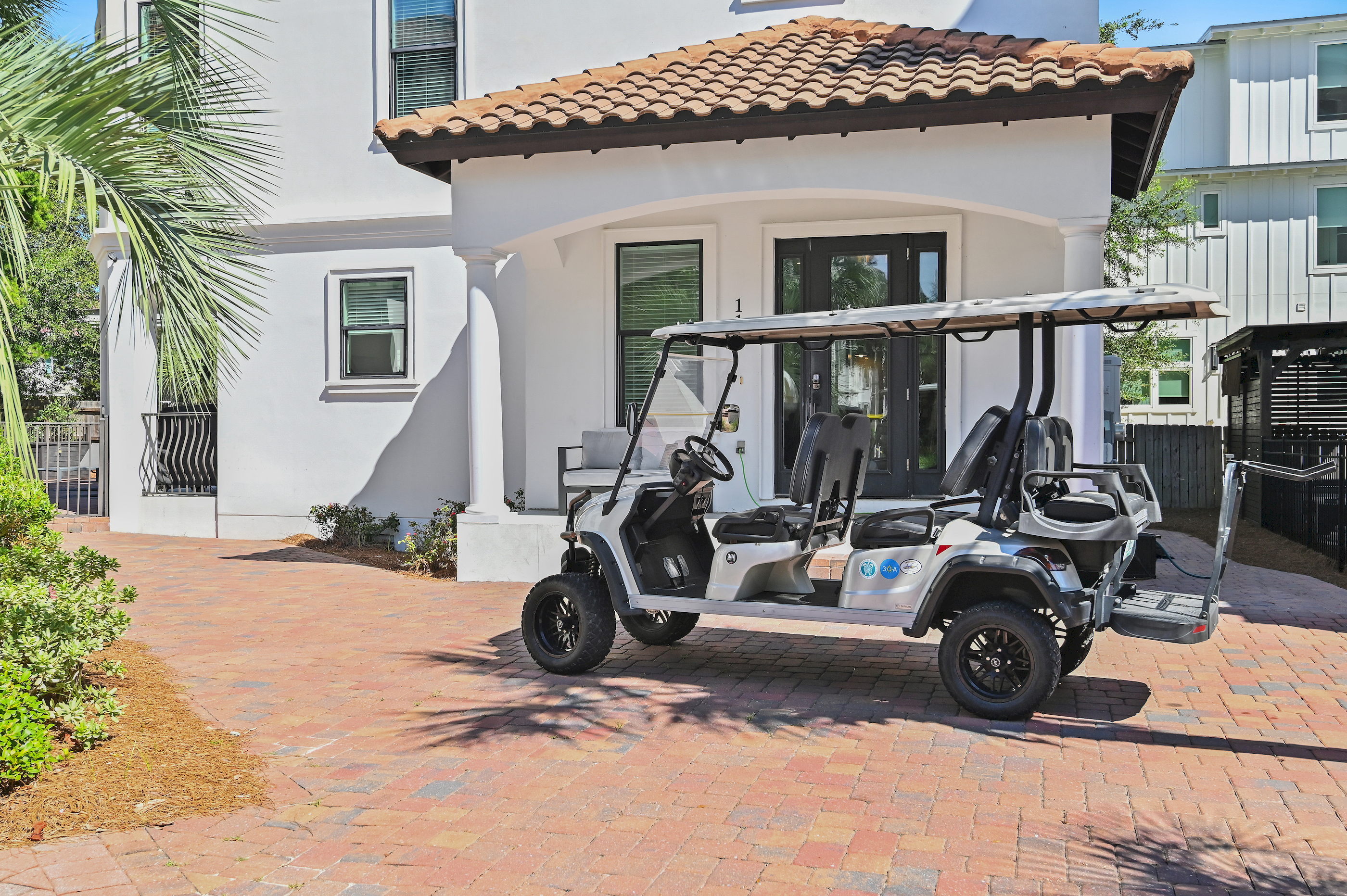 Bright and inviting exterior with a spacious brick courtyard and golf cart.