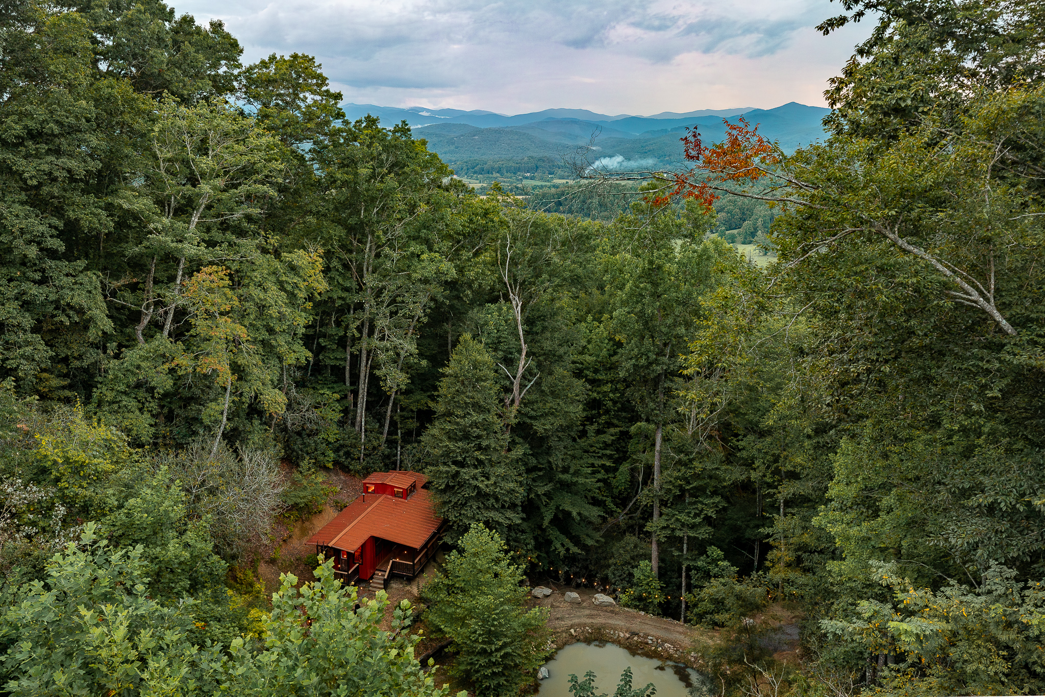 {Hidden Caboose} Follow the private forest trail to the tucked-away red caboose, with Blue Ridge Mountain views rising beyond the trees.