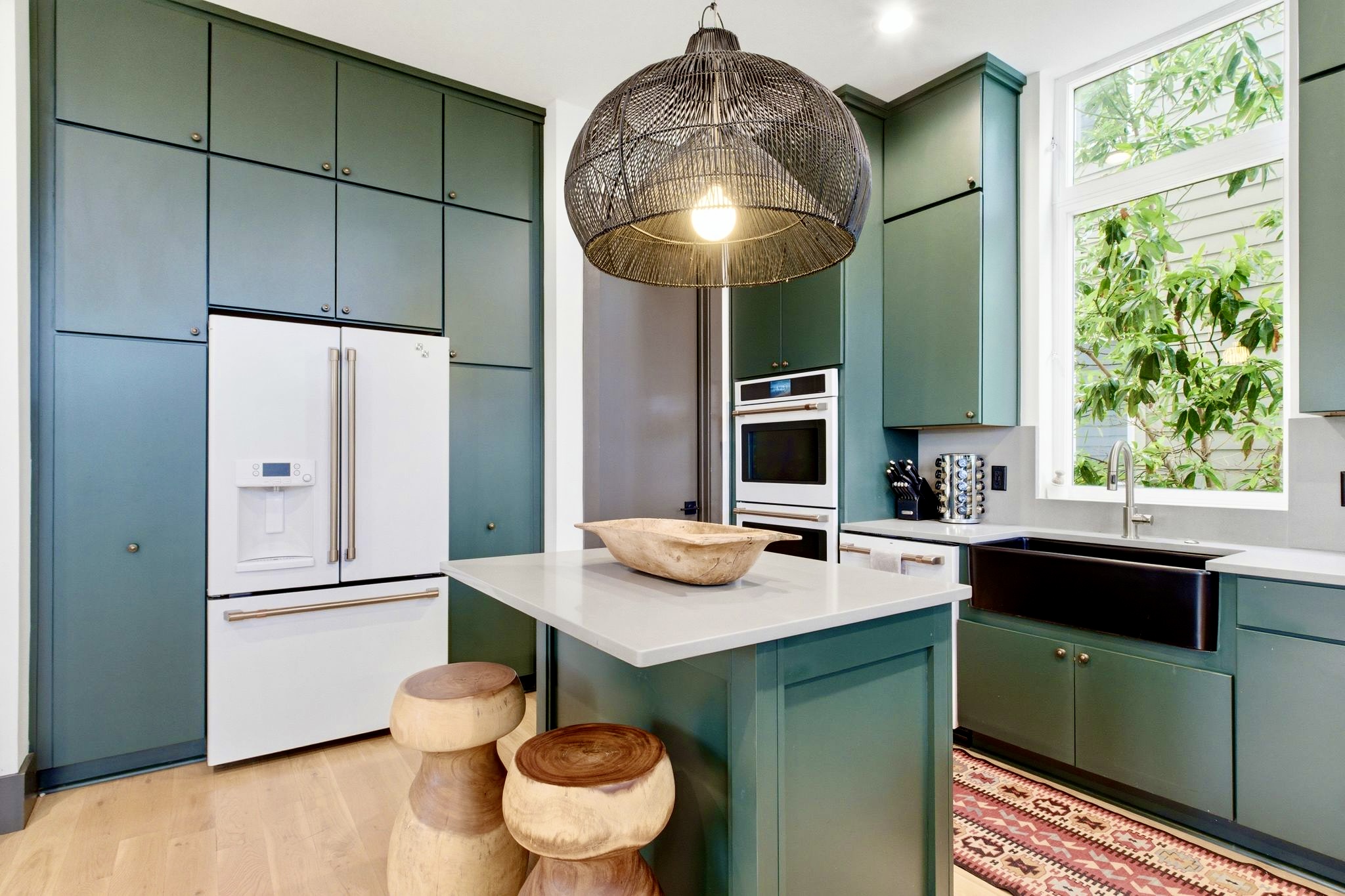 Sleek kitchen corner w/ stainless appliances, teal lower cabinets & open flow into the living area.
