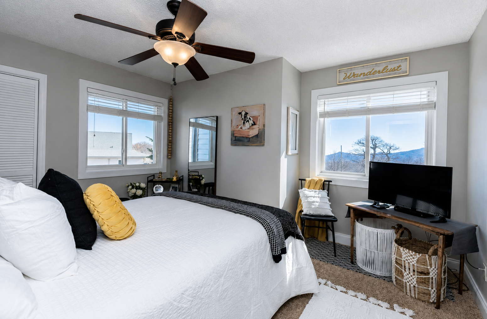 Bedroom with a mountain view. Furniture configuration has been updated to include wall mounted TV, with the table and chair under the window for a dedicated work space.