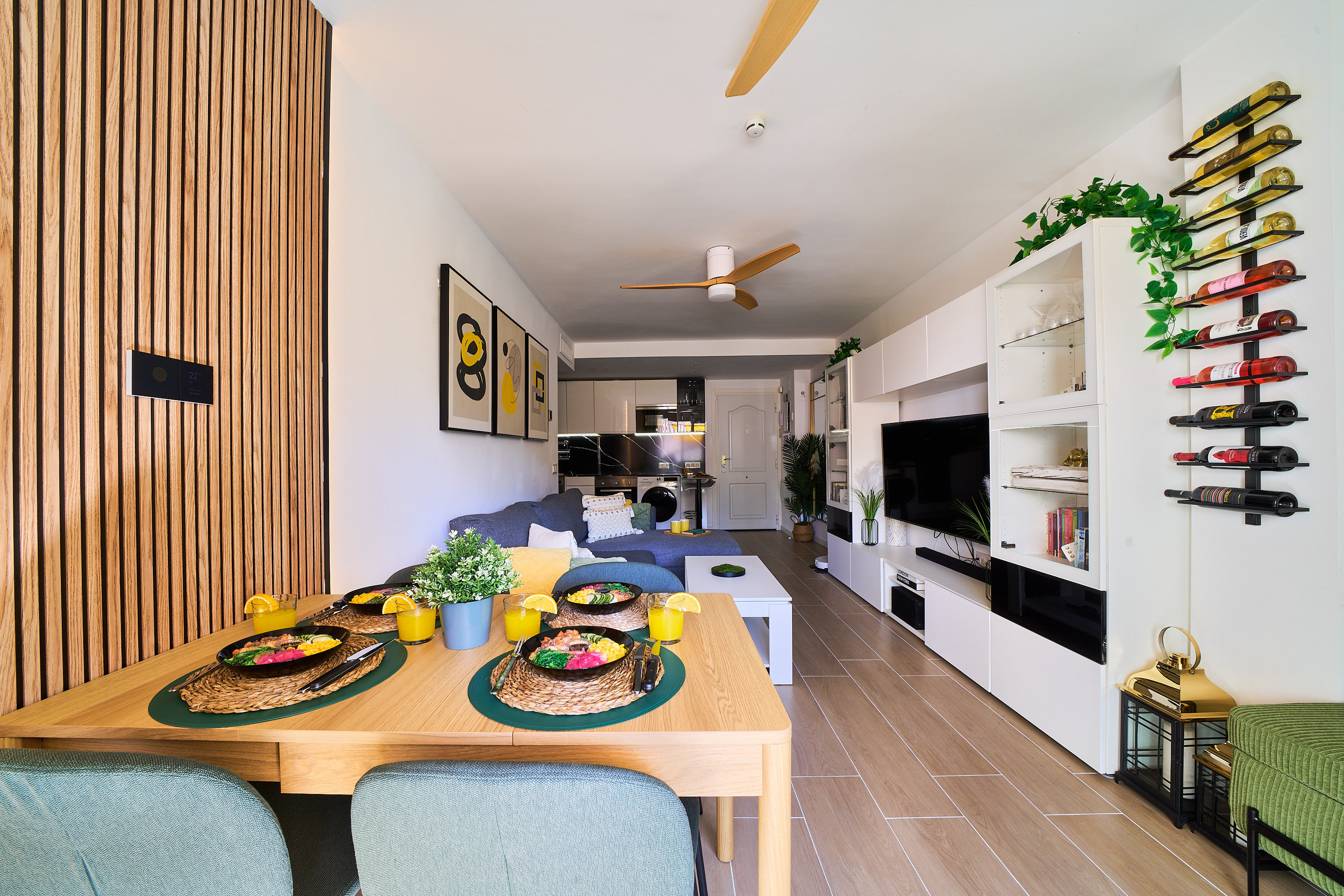 Stylish open-plan living room with a modern kitchen, smart TV, and natural light throughout — ideal for relaxing or sharing a glass of wine after a day by the beach.
