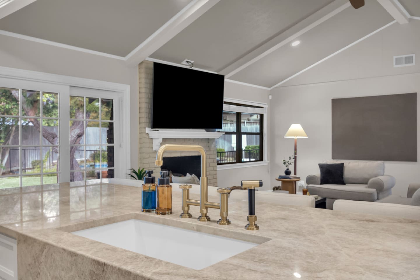 Open-concept living and kitchen area featuring a 70” Smart TV, fireplace, spacious seating, luxe kitchen with granite countertops, five-burner gas stove, double oven, island seating, and a fully stocked coffee bar.