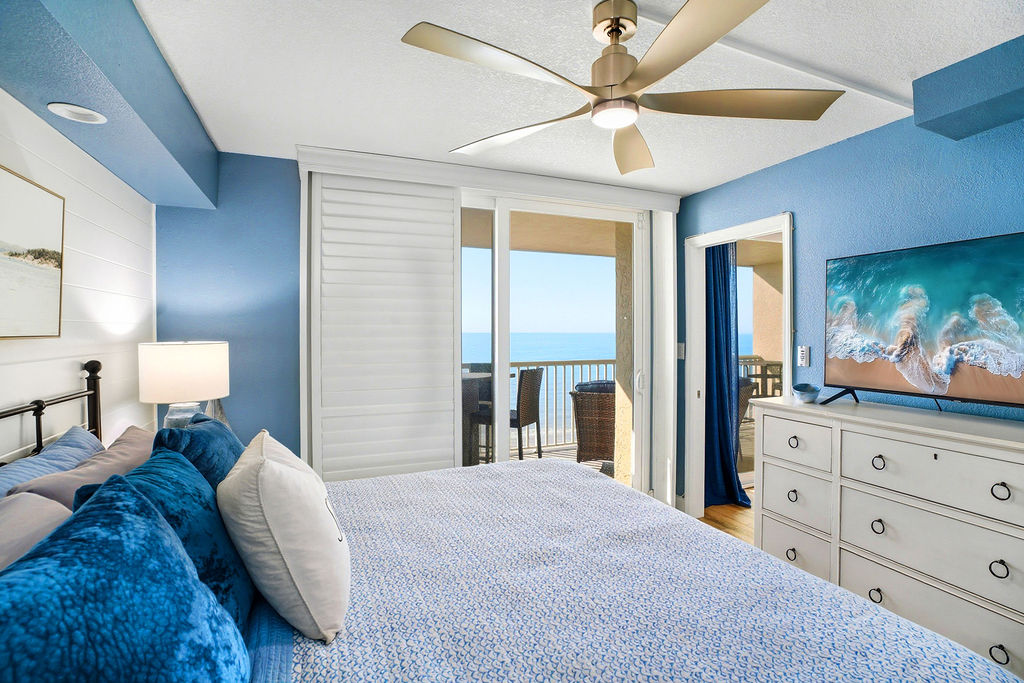 Beachfront master bedroom with private balcony access, ocean views, and comfortable king bed and smart TV.