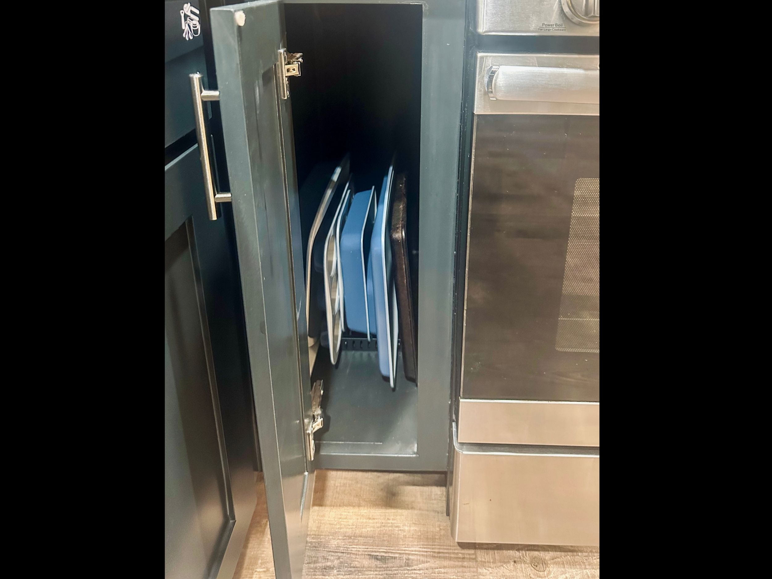 Kitchen cabinet neatly arranged with baking pans and sheets for effortless meal prep and home-style baking.