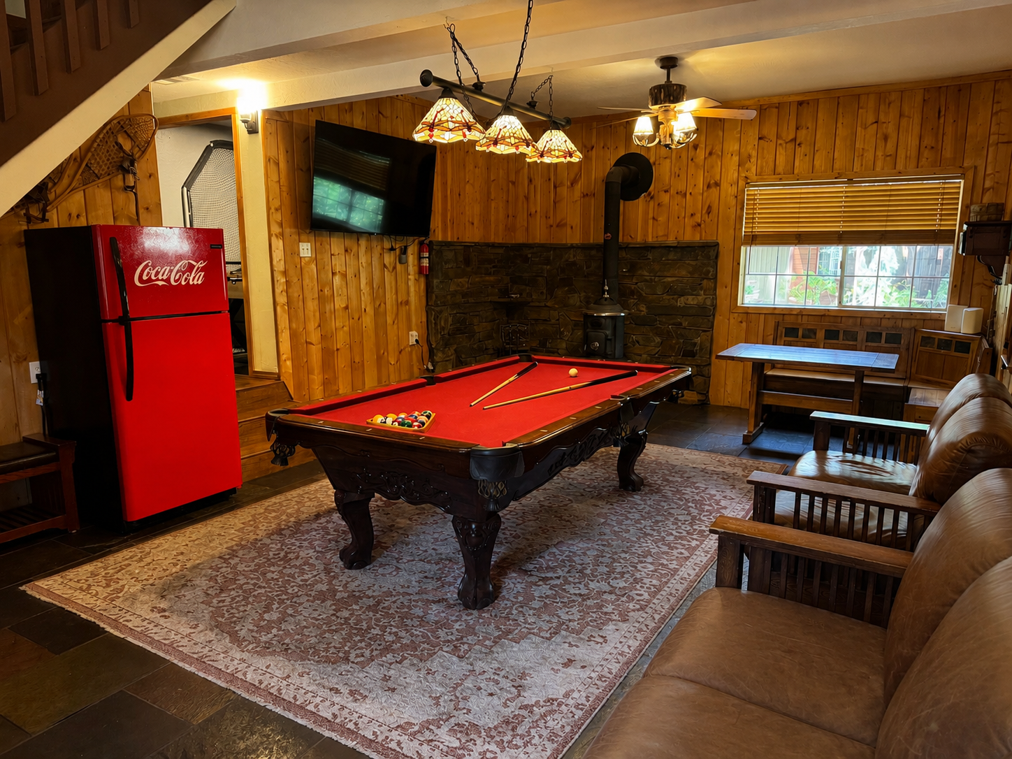 Step into the first room, featuring a pool table, smart TV, and a wood-burning fireplace. Sofas and a table provide a cozy spot to unwind and entertain.