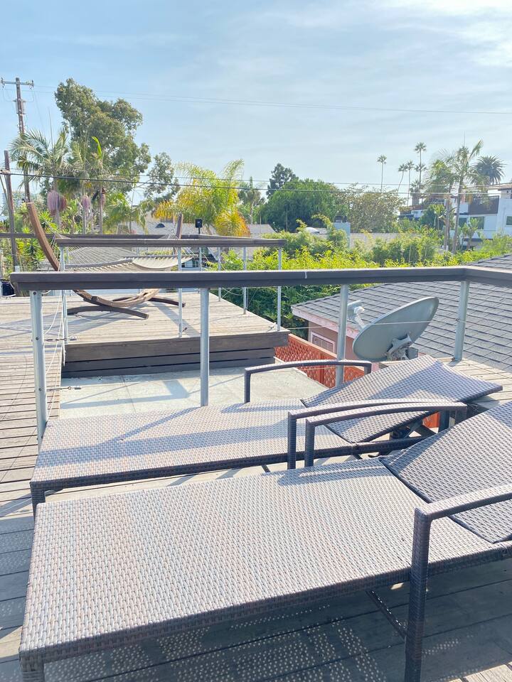 Sunny rooftop terrace with lounge chairs and a relaxing view.