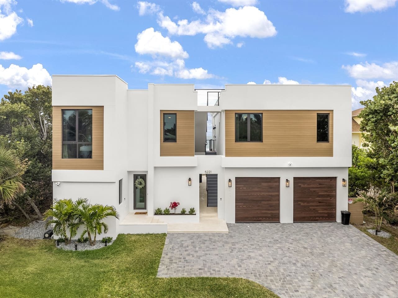 Capture the full exterior of the house with a welcoming door entrance, lush greenery and trees, convenient parking lots, sleek glass windows, and a stylish color scheme, all set on elegant flooring for a modern, inviting vibe
