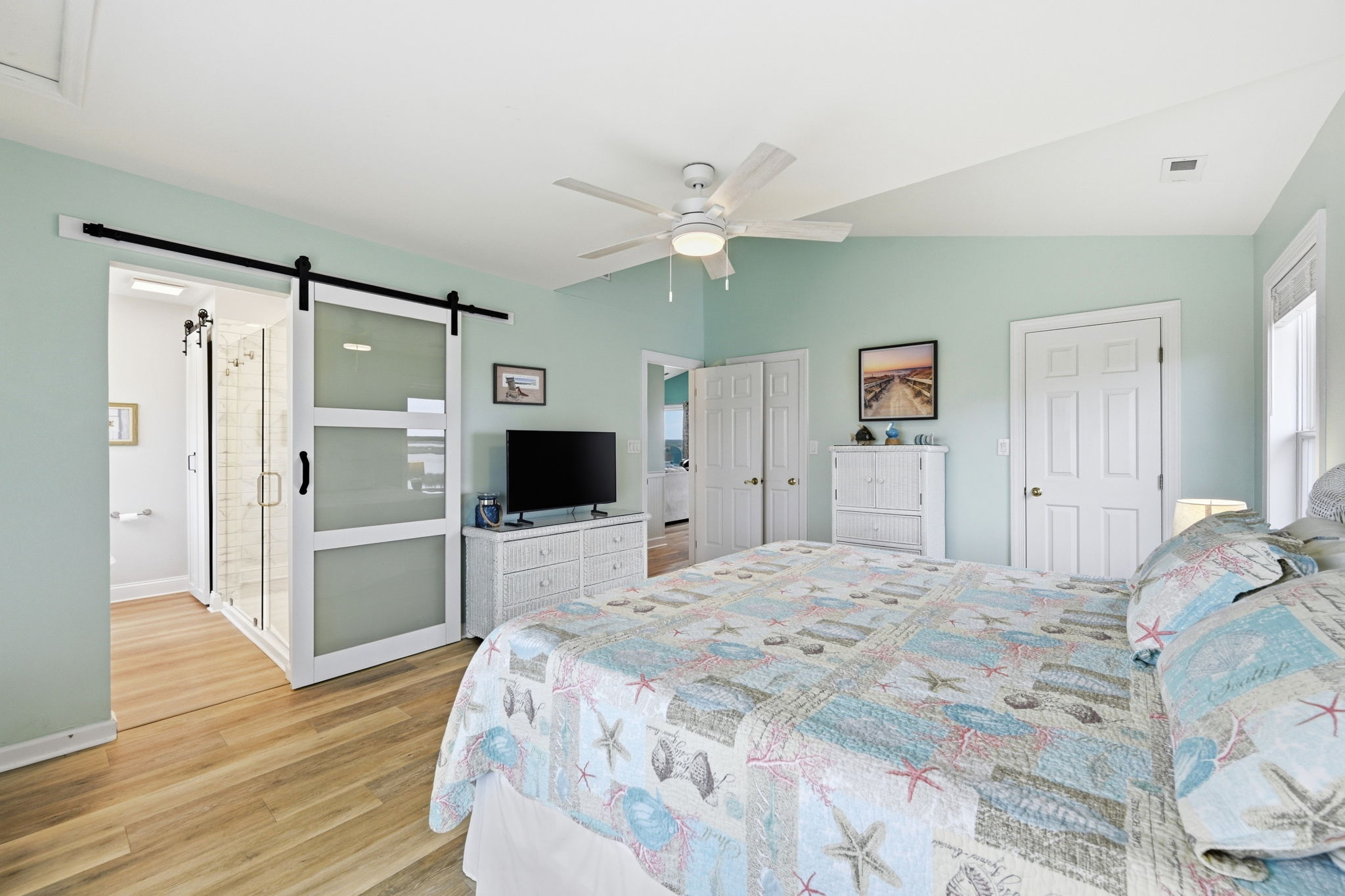 Rest easy in this spacious bedroom featuring a comfortable king sized bed, elevated ceilings, ceiling fan, and a spa-like ensuite bathroom