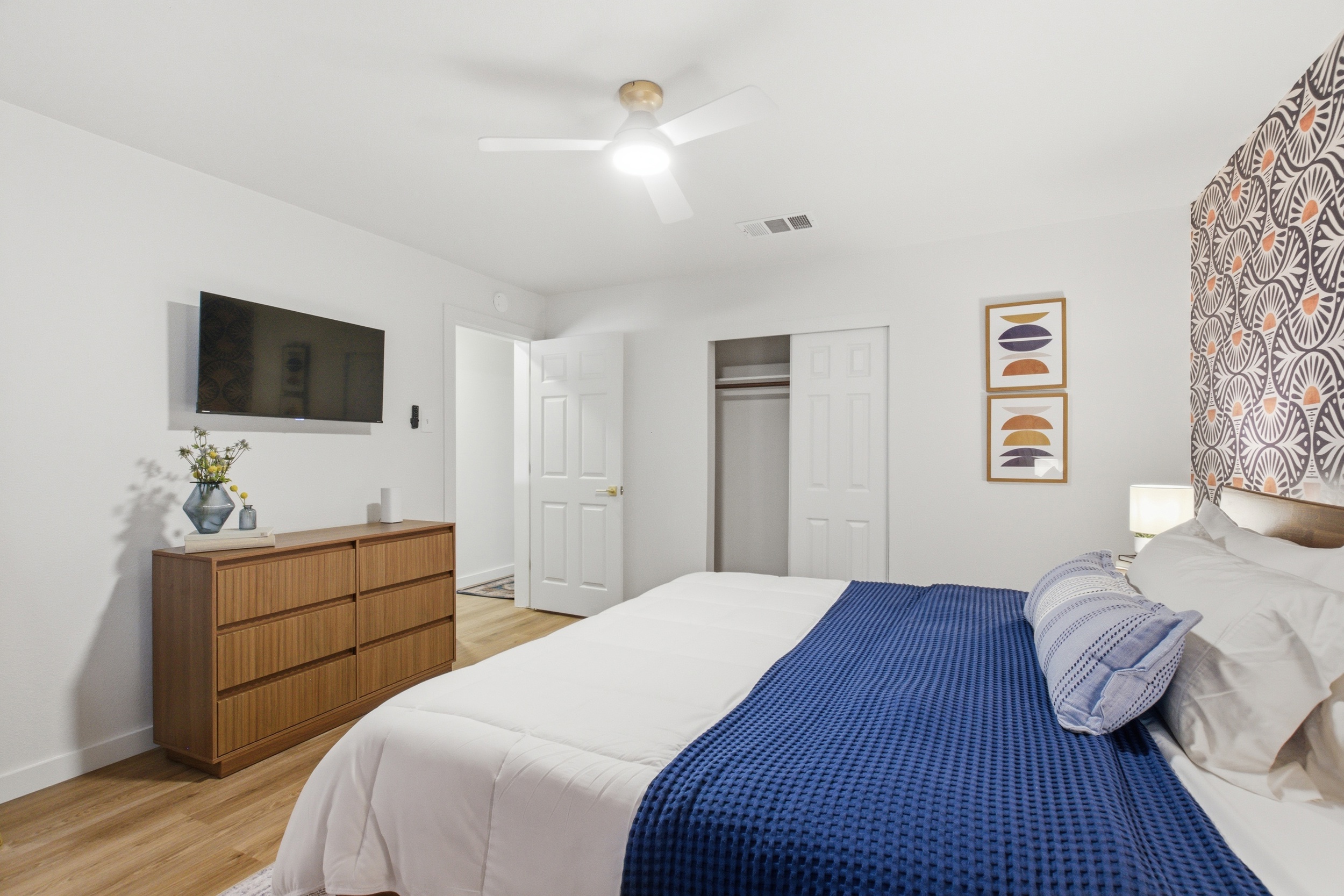 Master bedroom with dresser, Smart TV, hardwood floors, and Portable Fan. Clothing storage, hangers, and ceiling fan included. 4-bedroom Arlington vacation rental sleeps 8.