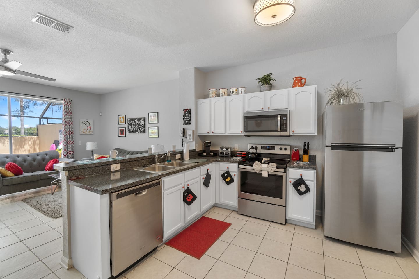 - Modern kitchen with stainless steel appliances and plenty of granite counters  
- White cabinetry pairs with bold red accents for a fresh and lively style  
- Open layout flows into the living space for easy cooking and entertaining  
